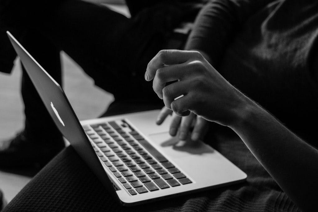 Man typing on laptop in black and white photo