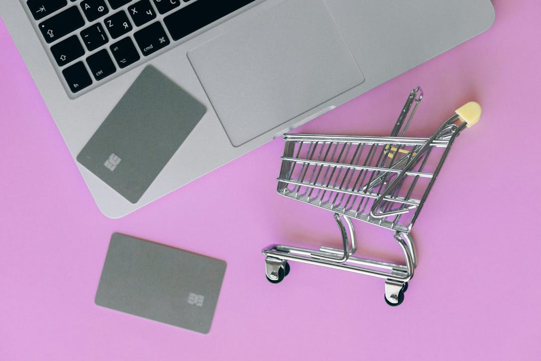 A shopping cart next to a laptop.