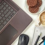 Cookies, Coffee Standing Next To A Laptop And Office Supplies On A Desk. Photo By Katja Burger.