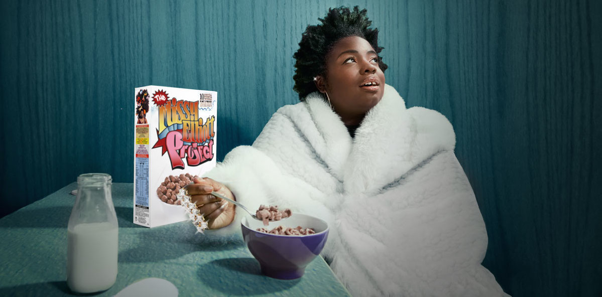 Photograph of Selina, a Black Woman, recreating a Missy Elliott image. She is sitting at a table wearing a white bath robe, with a box and bowl of cereal next to her.