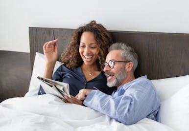 Man and woman in bed reading a magazine