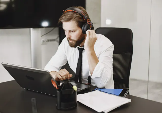 Professionnel utilisant un softphone sur ordinateur avec un casque audio au bureau