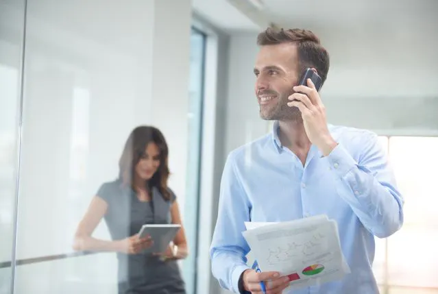 Professionnel en appel avec un smartphone utilisant un forfait mobile professionnel