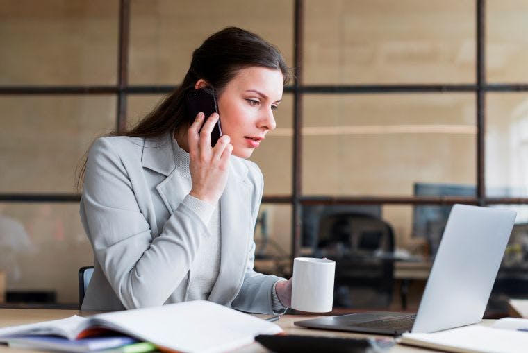 femme au travail laissant un message vocal par téléphone