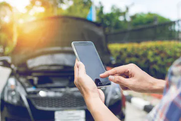Driver using a smartphone to call roadside assistance included in a vehicle service contract for a mechanical breakdown.