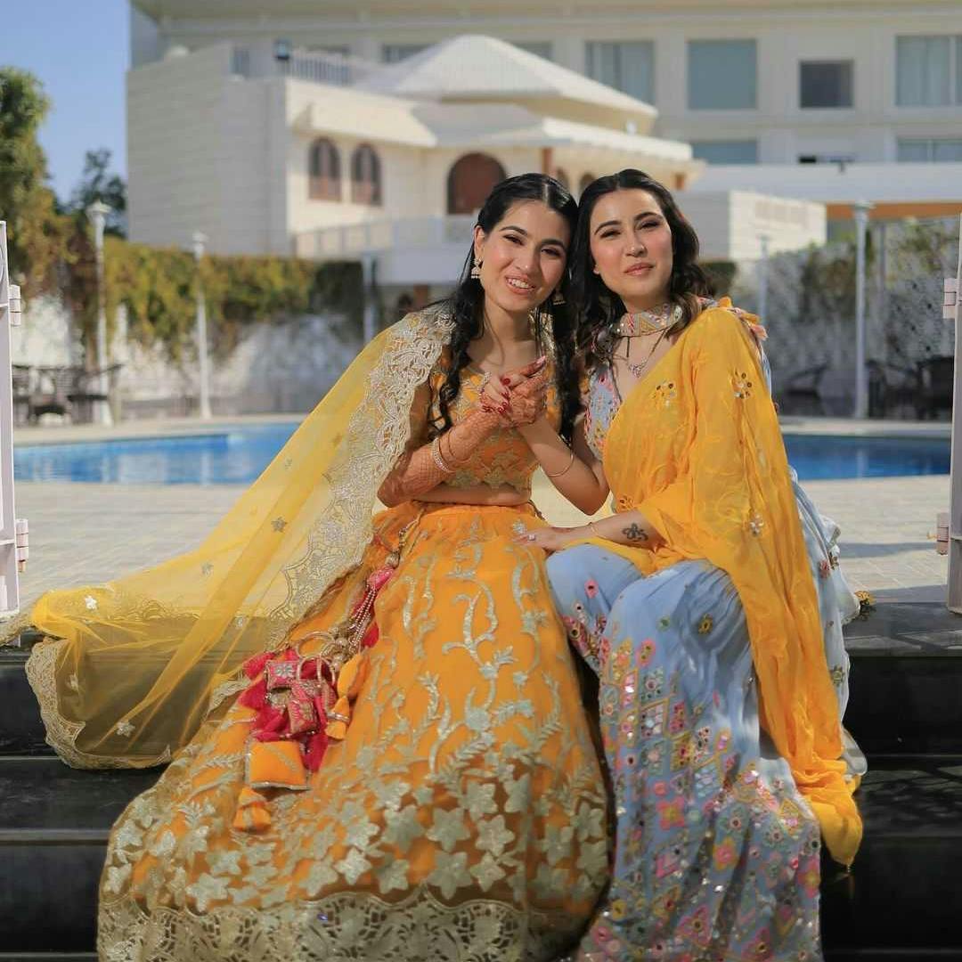bride posing with sister on haldi ceremony
