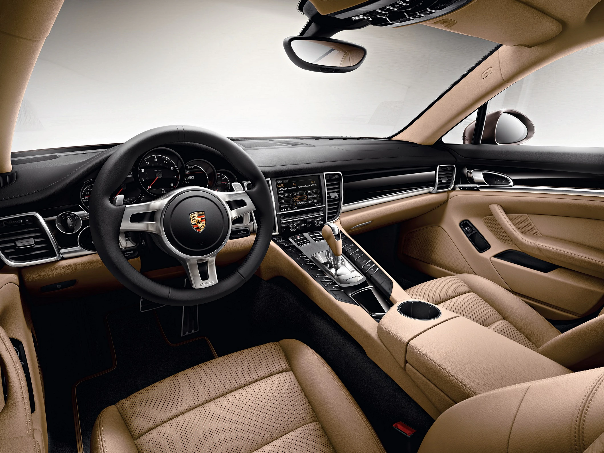 Innenraum eines Luxusautos mit beigen Ledersitzen, einem schwarzen Armaturenbrett und einem Multifunktionslenkrad.