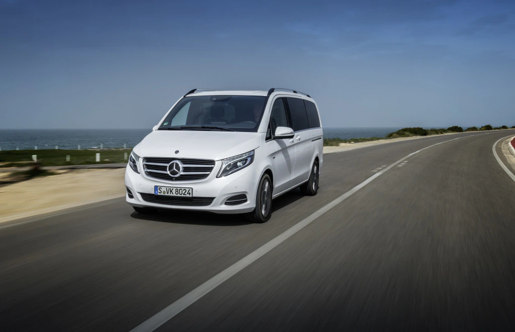 Weißer Mercedes-Van fährt auf einer Küstenstraße bei klarem Himmel.