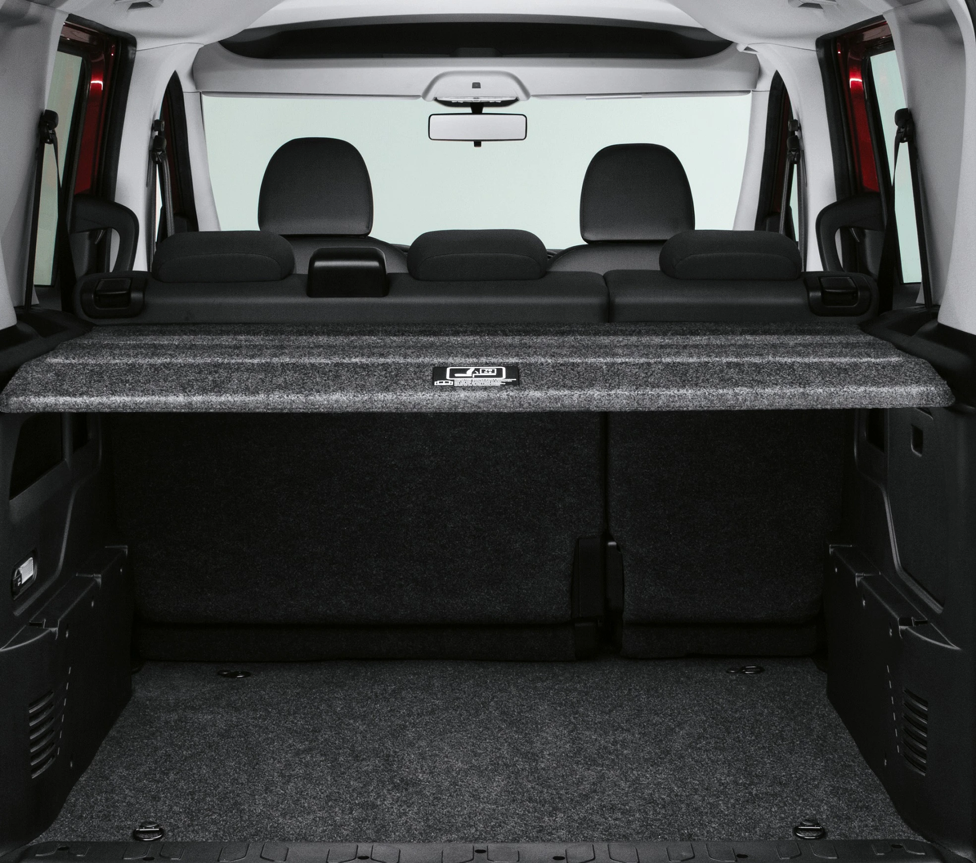 Kofferraum eines Autos mit umgeklappten Rücksitzen, grauer Teppichboden und schwarze Kopfstützen sichtbar.