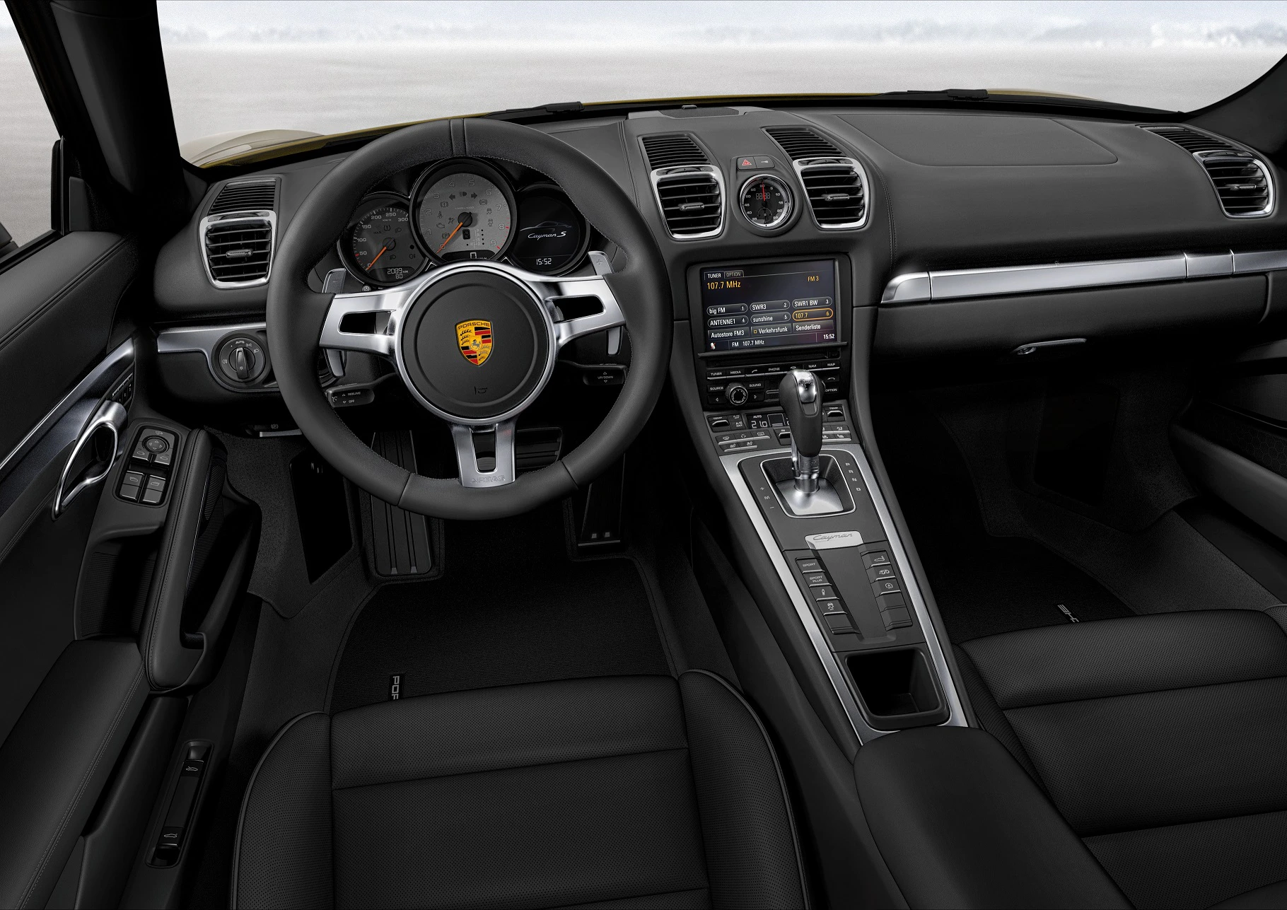 Innenraum eines sportlichen Autos mit modernen Armaturenbrett, digitalem Display und lederbezogenen Sitzen. Lenkrad trägt ein Autoemblem.