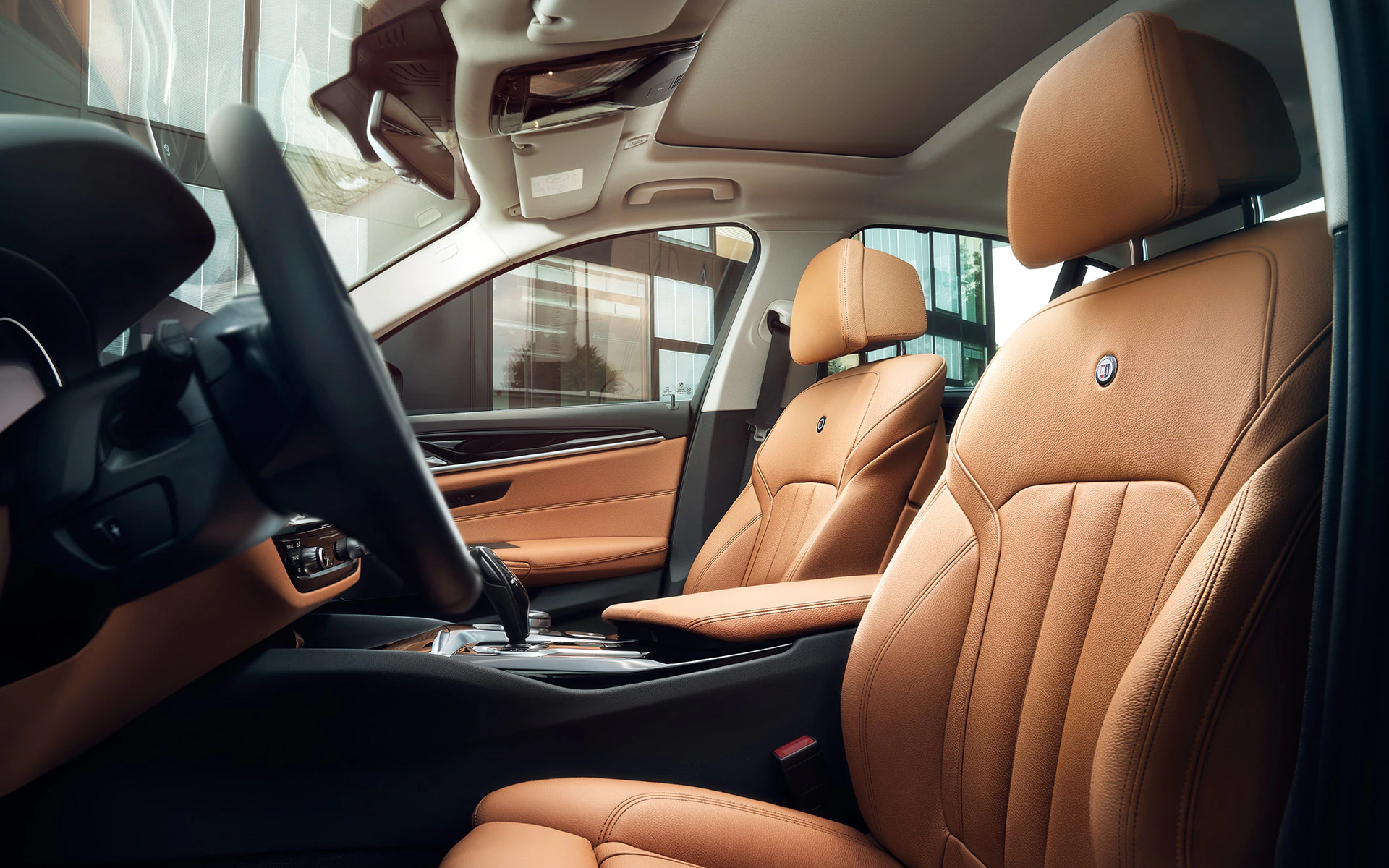 Innenraum eines Autos mit luxuriöser brauner Lederausstattung, modernem Armaturenbrett und glänzendem Lenkrad.