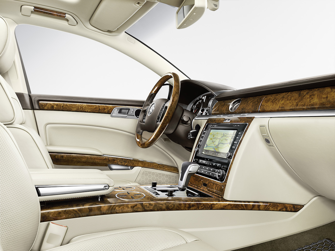 Innenraum eines luxuriösen Autos mit cremefarbenem Leder, Holzelementen und einem modernen Infotainment-System auf der Mittelkonsole.