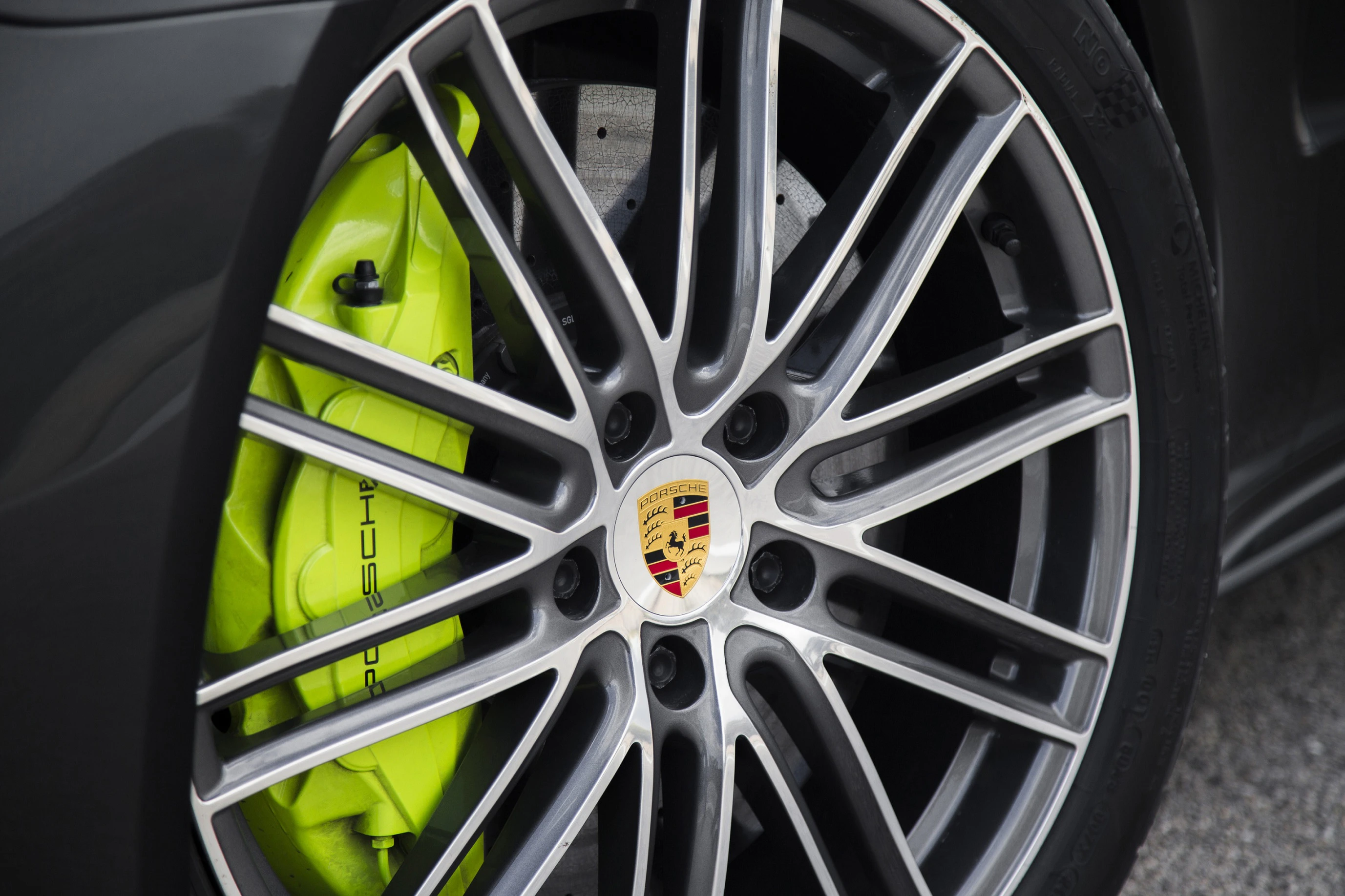 Nahaufnahme eines Porsche-Rades mit gelbem Bremssattel und sichtbarem Logo auf glänzender Felge.
