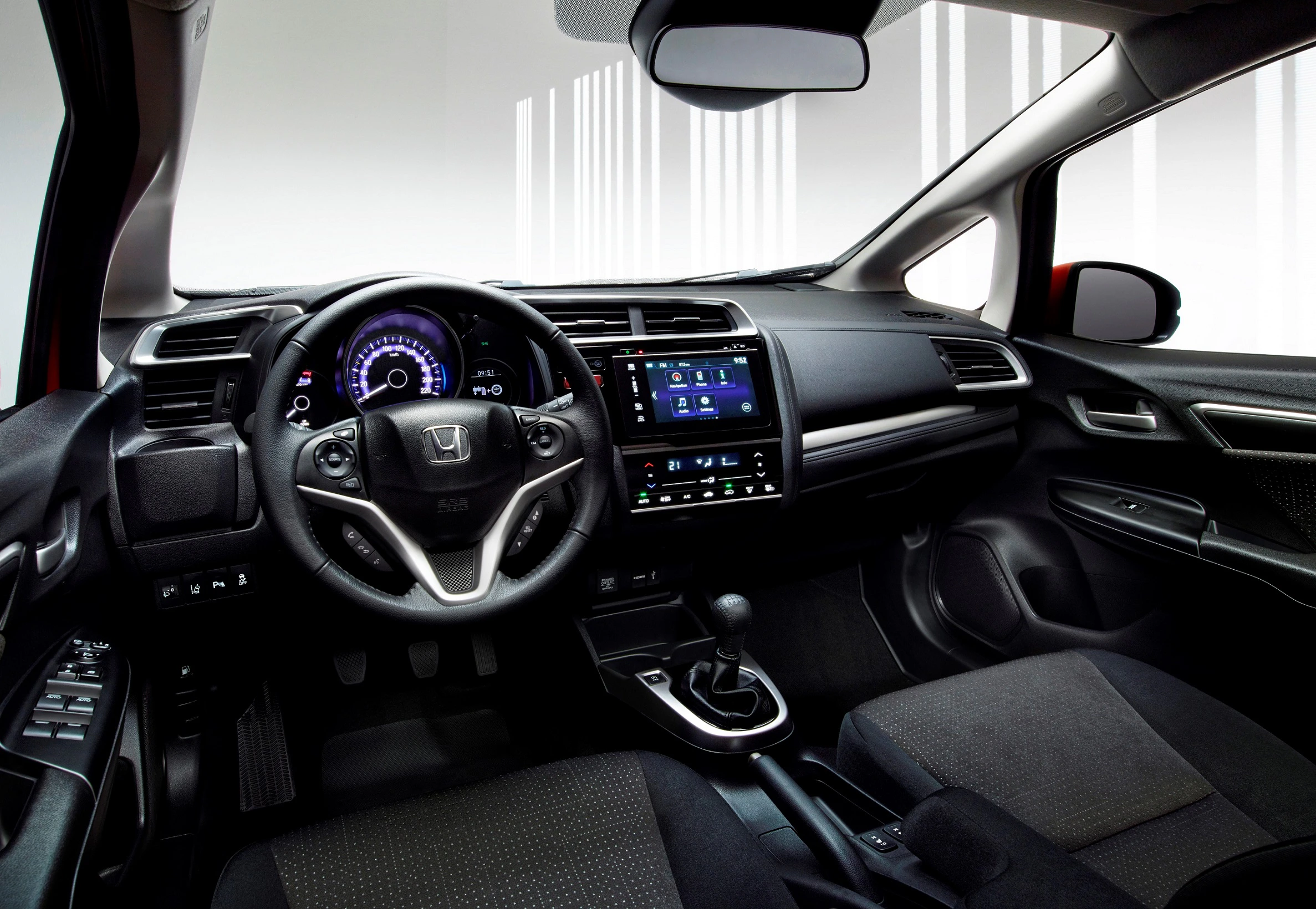 Innenraum eines Autos mit modernem Armaturenbrett, Lenkrad, Schaltknauf und Touchscreen-Display. Dunkle Polsterung und elegante Details.