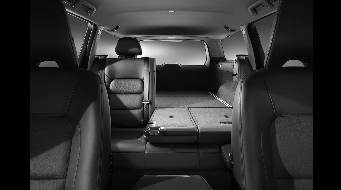 Innenraum eines Autos mit umgeklappter Rückbank, die einen erweiterten Laderaum zeigt. Schwarz-weiße Fotografie, moderne Ledersitze.