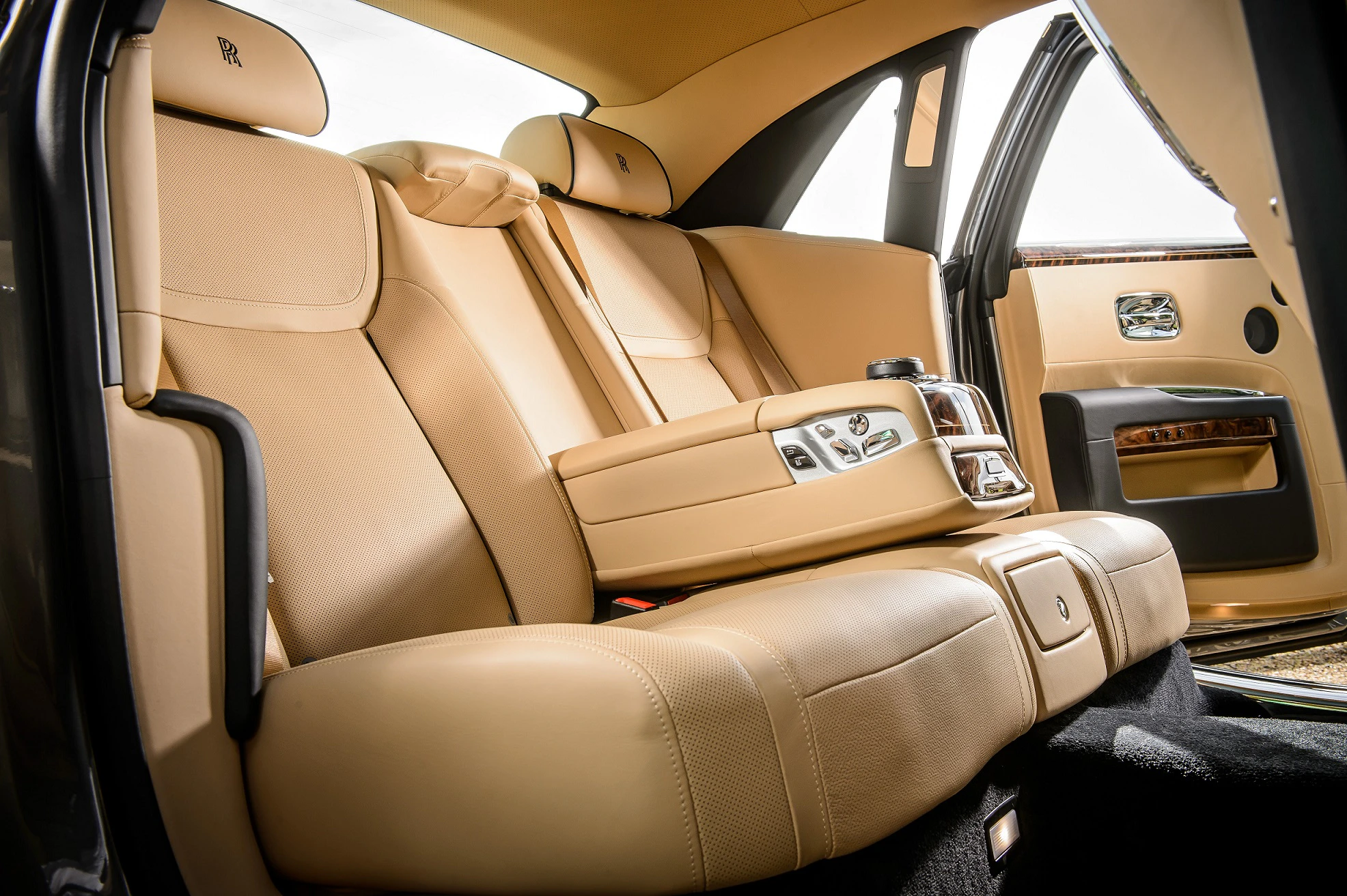 Luxuriöser Innenraum eines Autos mit beigen Ledersitzen, einer Mittelkonsole mit Getränkehaltern und offenem Fond.