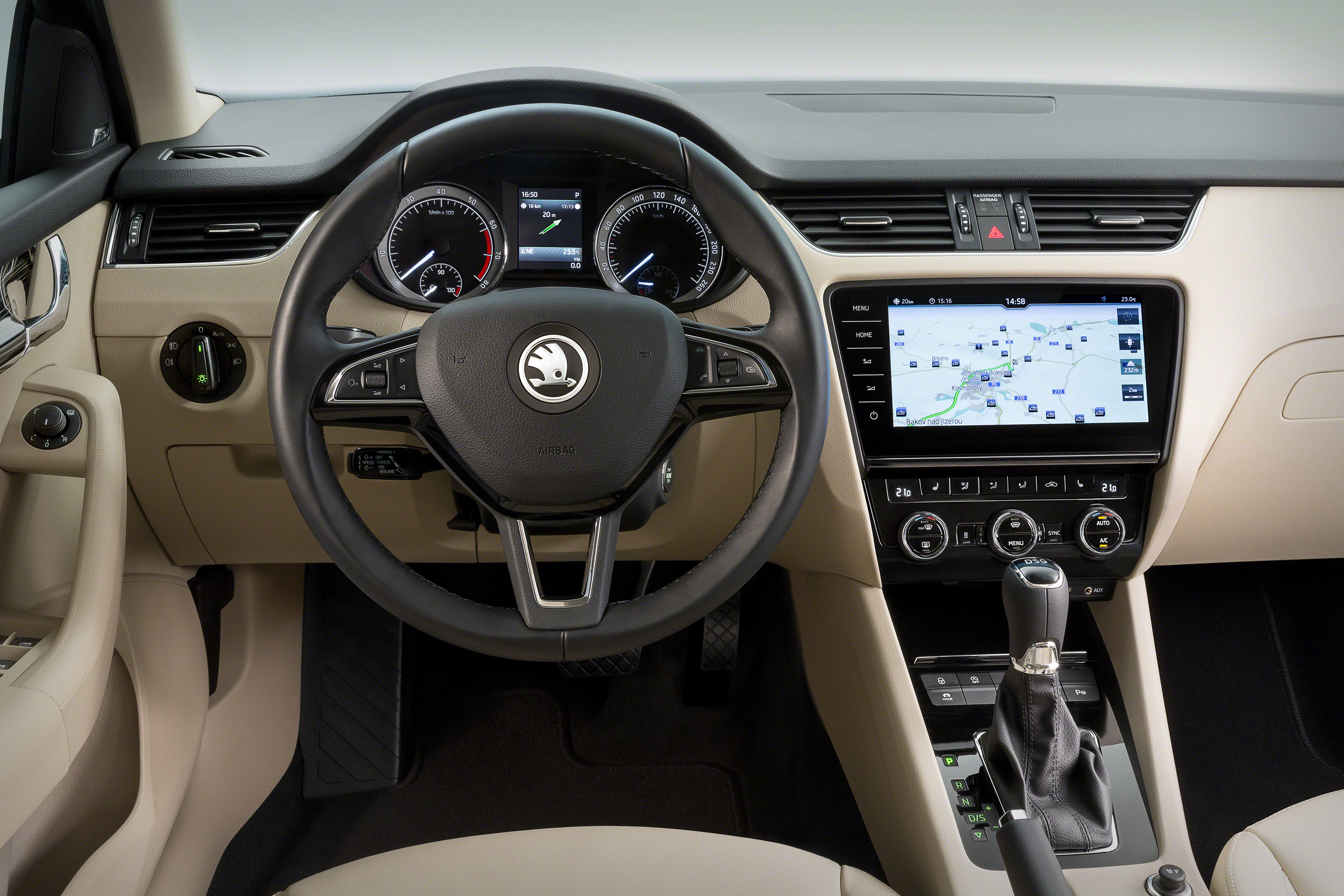 Innenraum eines Autos mit Steuerung, Tacho, Navigationssystem und Schalthebel. Modernes Design in Beige und Schwarz.