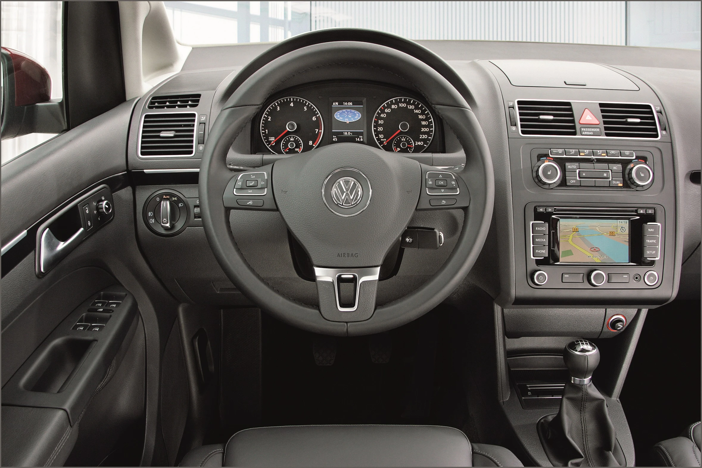 Innenraum eines Autos mit Volkswagen-Logo, Lenkrad, Armaturenbrett mit Tachoanzeige, Navigationssystem und manueller Schaltung.