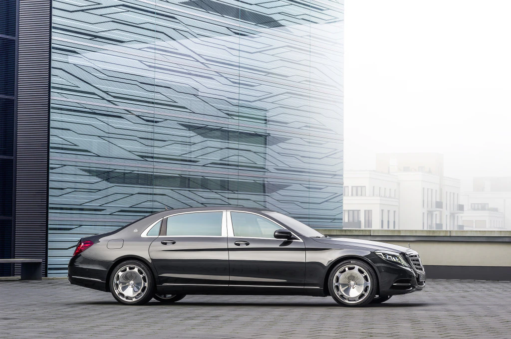 Schwarze Luxuslimousine vor moderner Gebäudefassade, seitlich aufgenommen, zeigt stilvolles Design und glänzende Felgen.