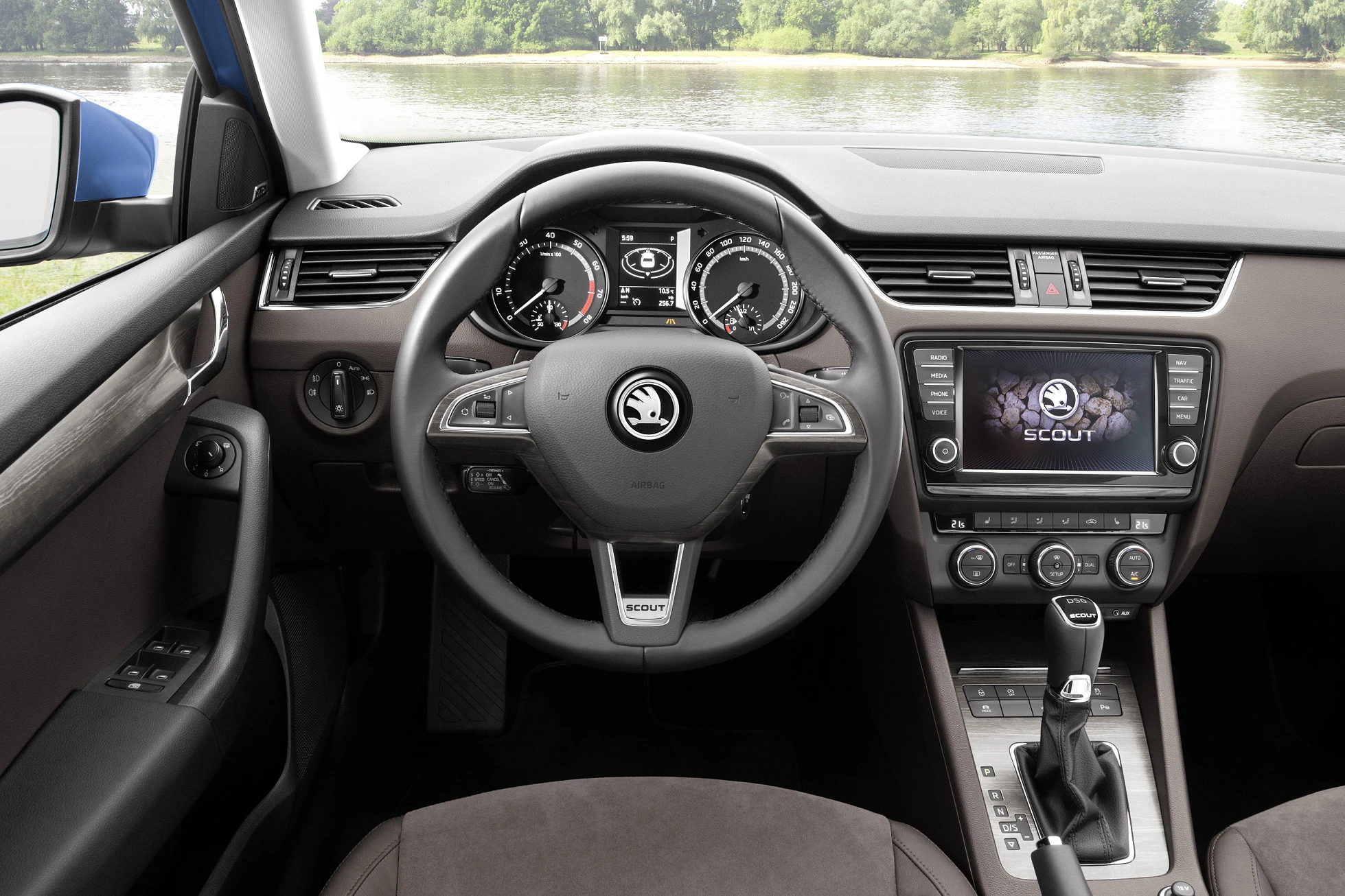 Innenraum eines Skoda Scout mit Fokus auf Lenkrad, Instrumententafel und Infotainmentsystem, entlang eines Flusses im Hintergrund.