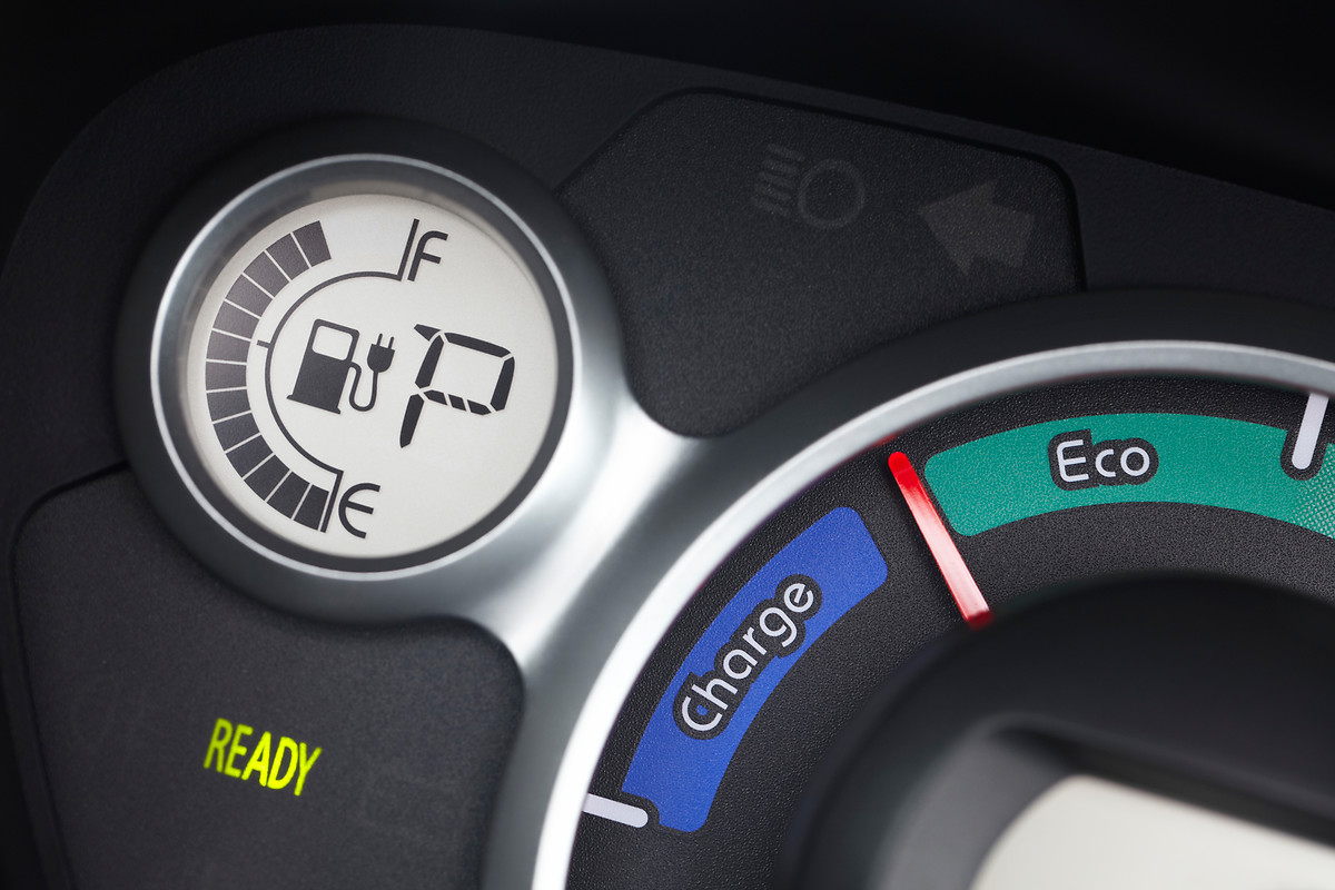 Nahaufnahme eines Elektroautoinstruments: Ladeanzeige, "Eco" und "Charge" Modus, Tankanzeige mit Stecker-Symbol, grünes "Ready"-Licht.