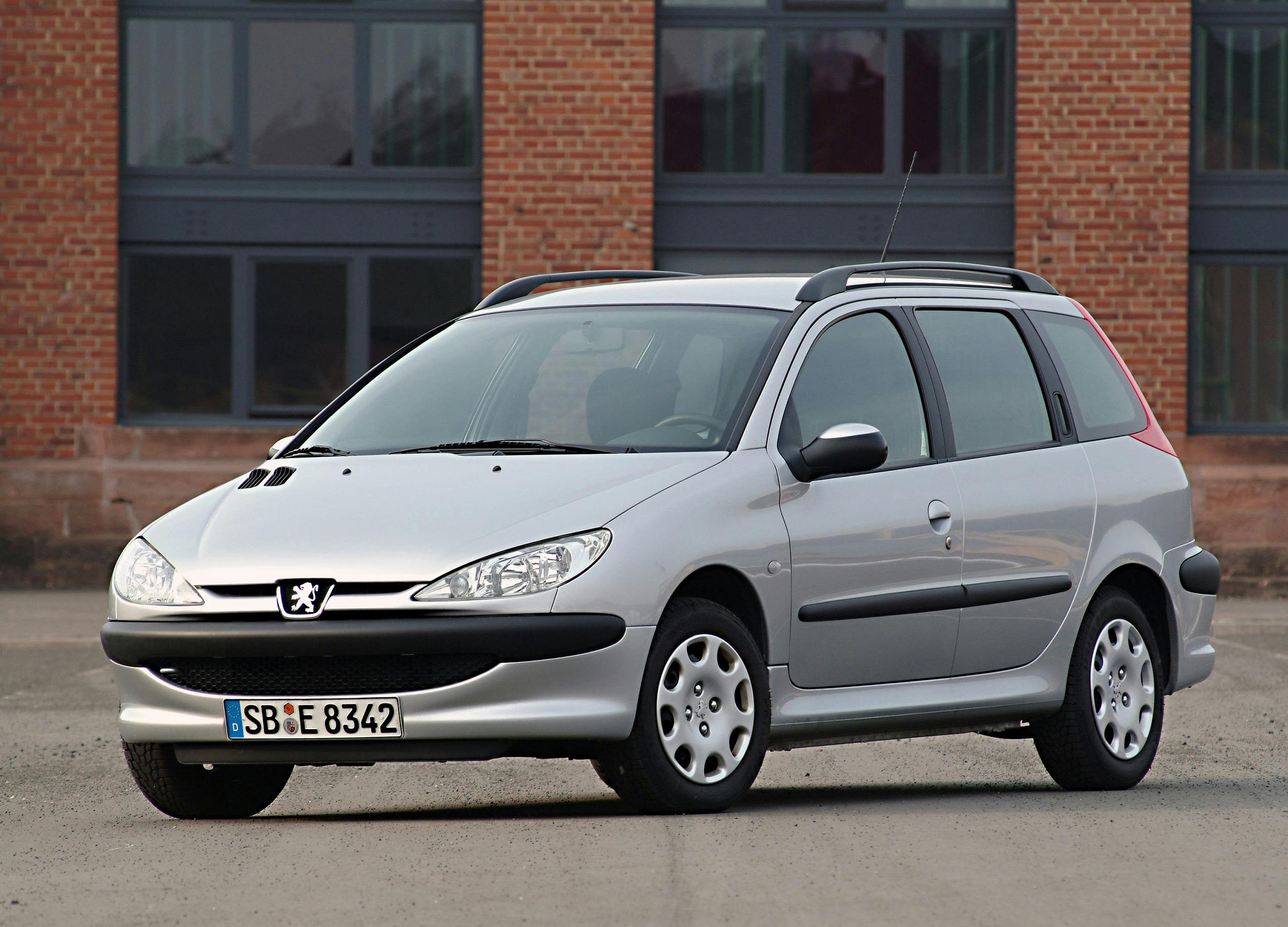 Silberner Peugeot 206 Kombi geparkt vor einem Backsteingebäude, Frontansicht.