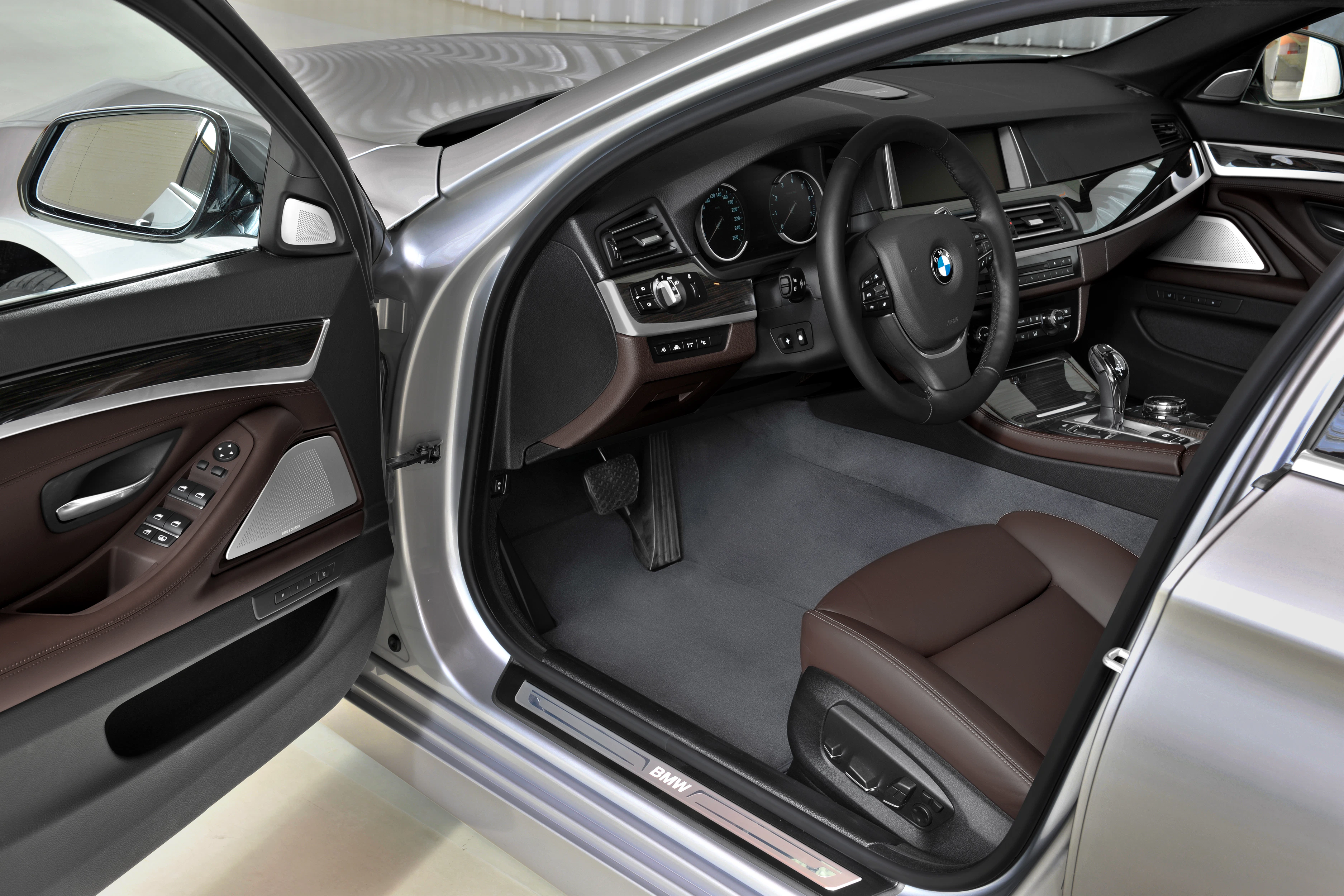Innenraum eines modernen BMW-Autos mit braunen Ledersitzen, multifunktionalem Lenkrad und einem Infotainmentsystem auf der Mittelkonsole.