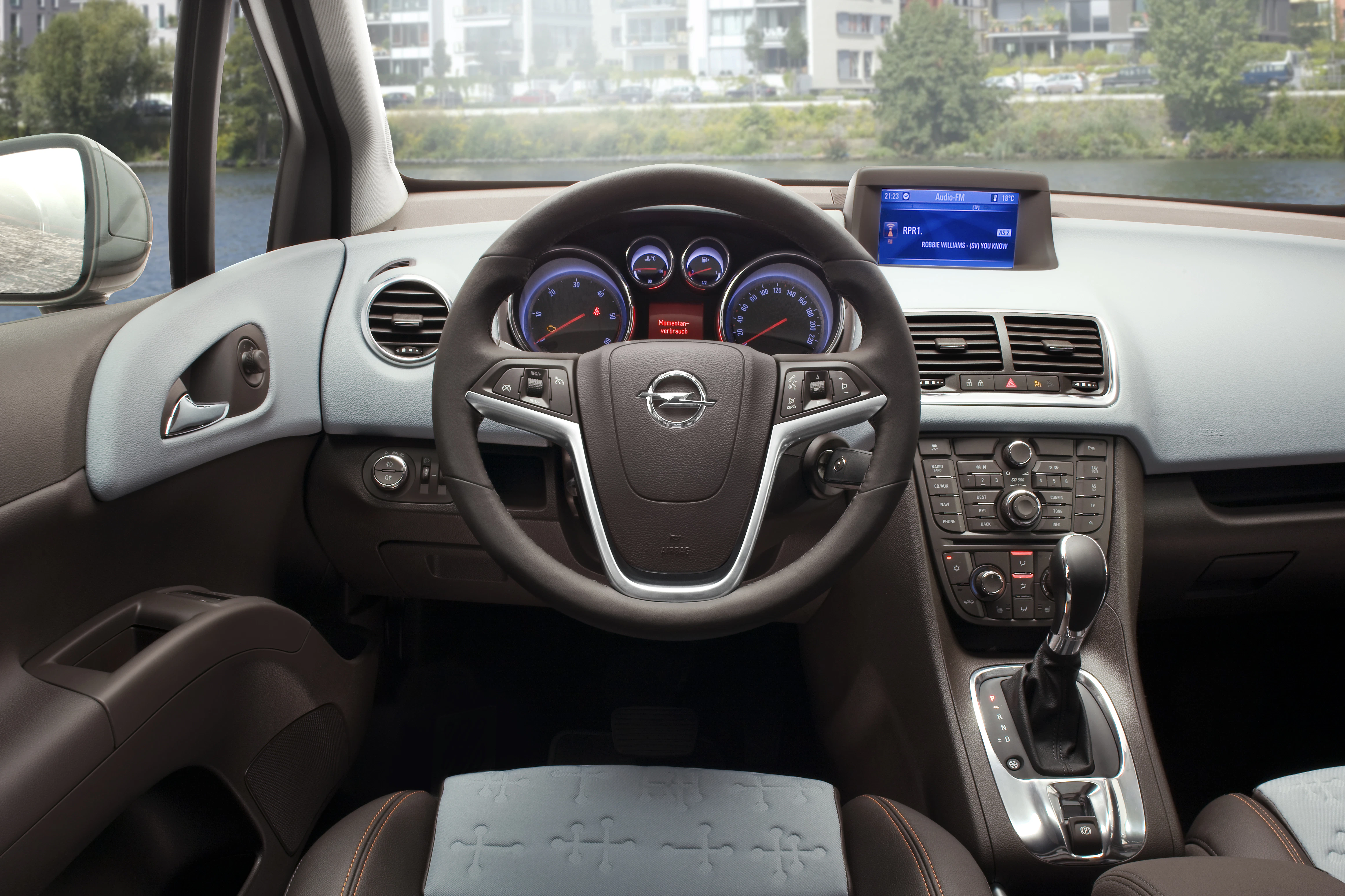 Innenraum eines Autos mit Opel-Logo auf dem Lenkrad, elektronischen Anzeigen und einem Display auf dem Armaturenbrett.