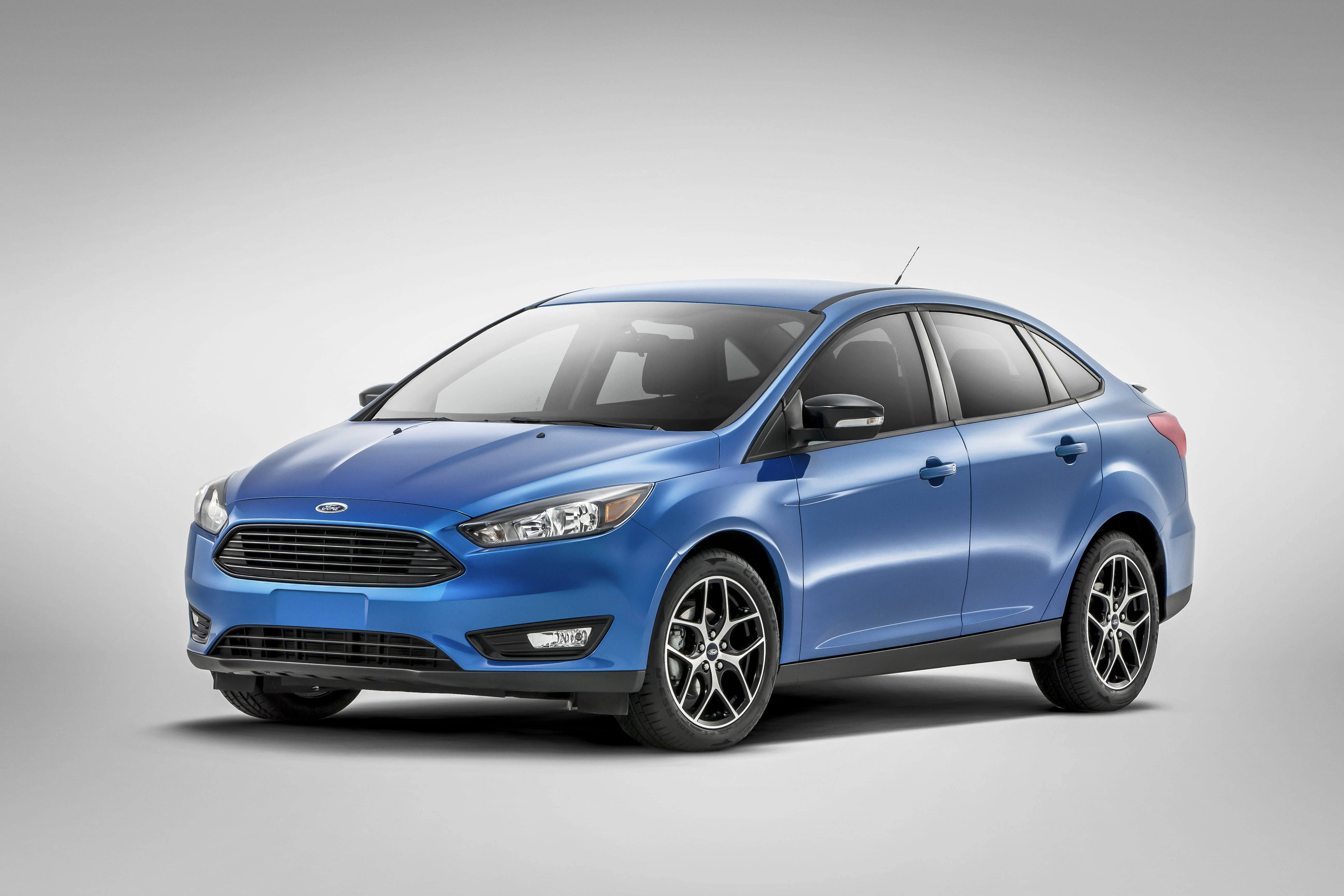Blauer Ford Focus Limousine vor grauem Hintergrund, von schräg vorn gesehen, mit schwarzen Felgen und markanter Frontpartie.