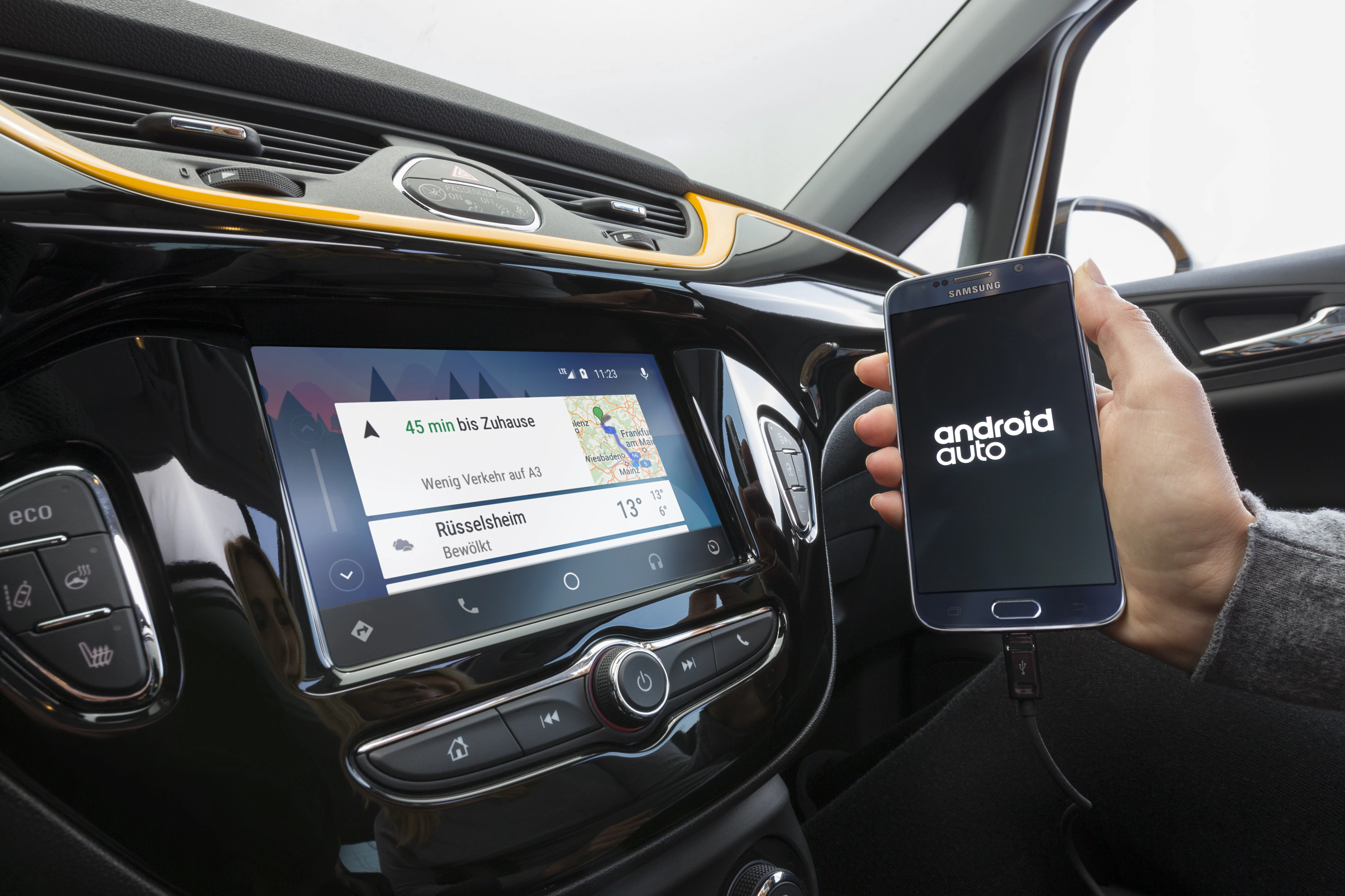 Person verbindet Android Auto über Smartphone mit dem Auto-Dashboard-Display. Navigations- und Wetterinformationen werden angezeigt.