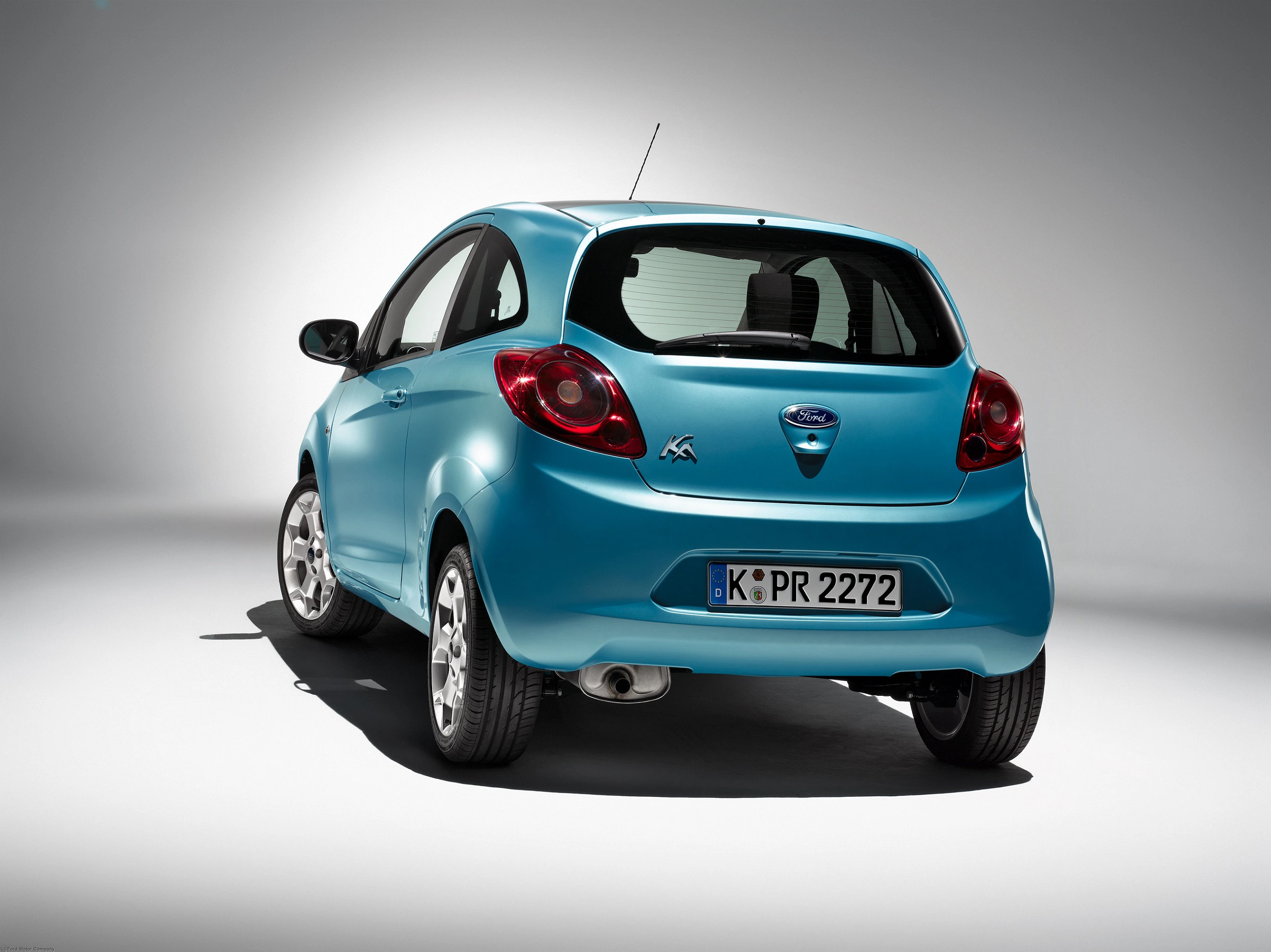Blauer Ford Ka, Rückansicht, mit Kölner Kennzeichen auf grauem Hintergrund beleuchtet.