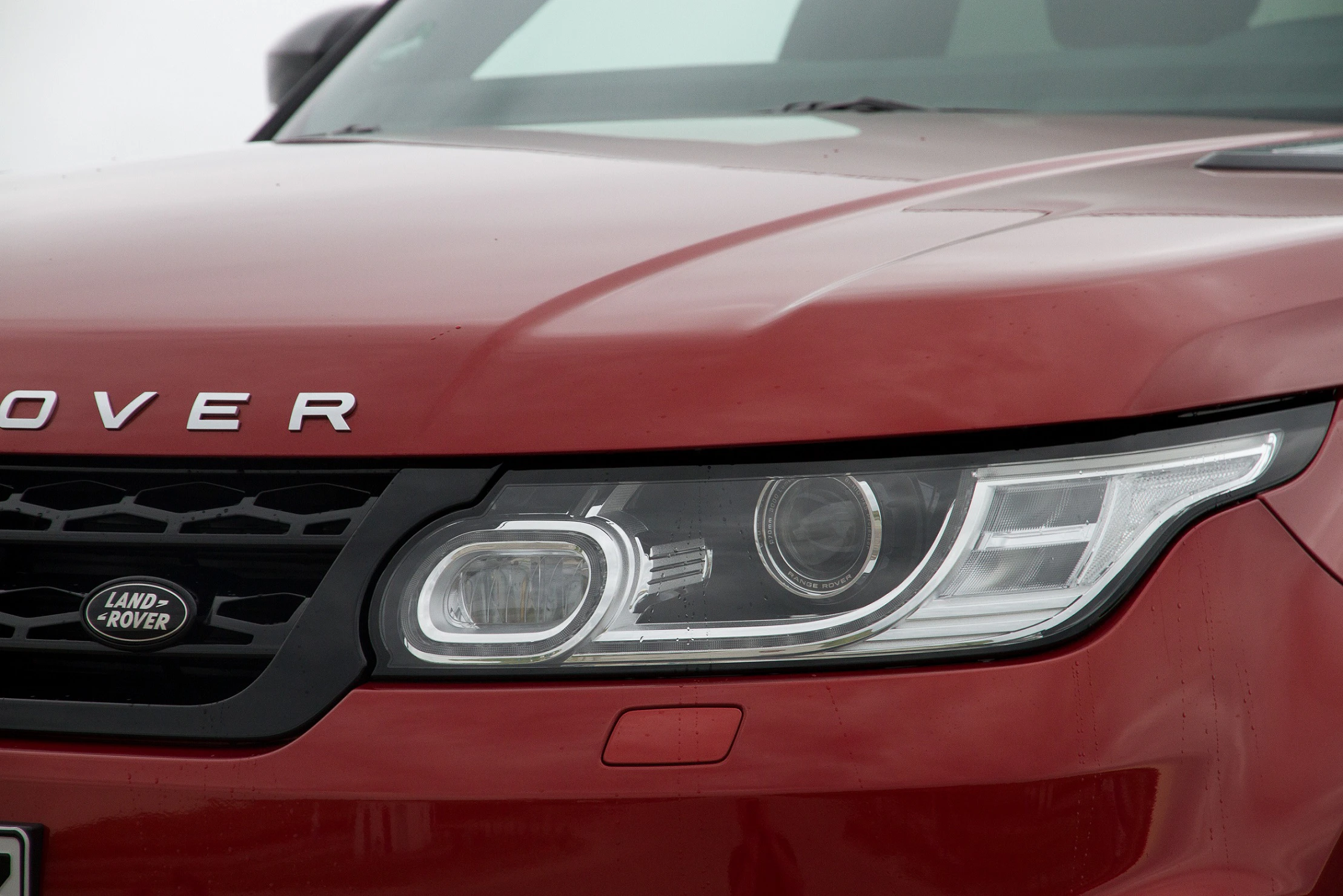 Roter SUV von Land Rover, Frontansicht mit Fokus auf Scheinwerfer und Kühlergrill.
