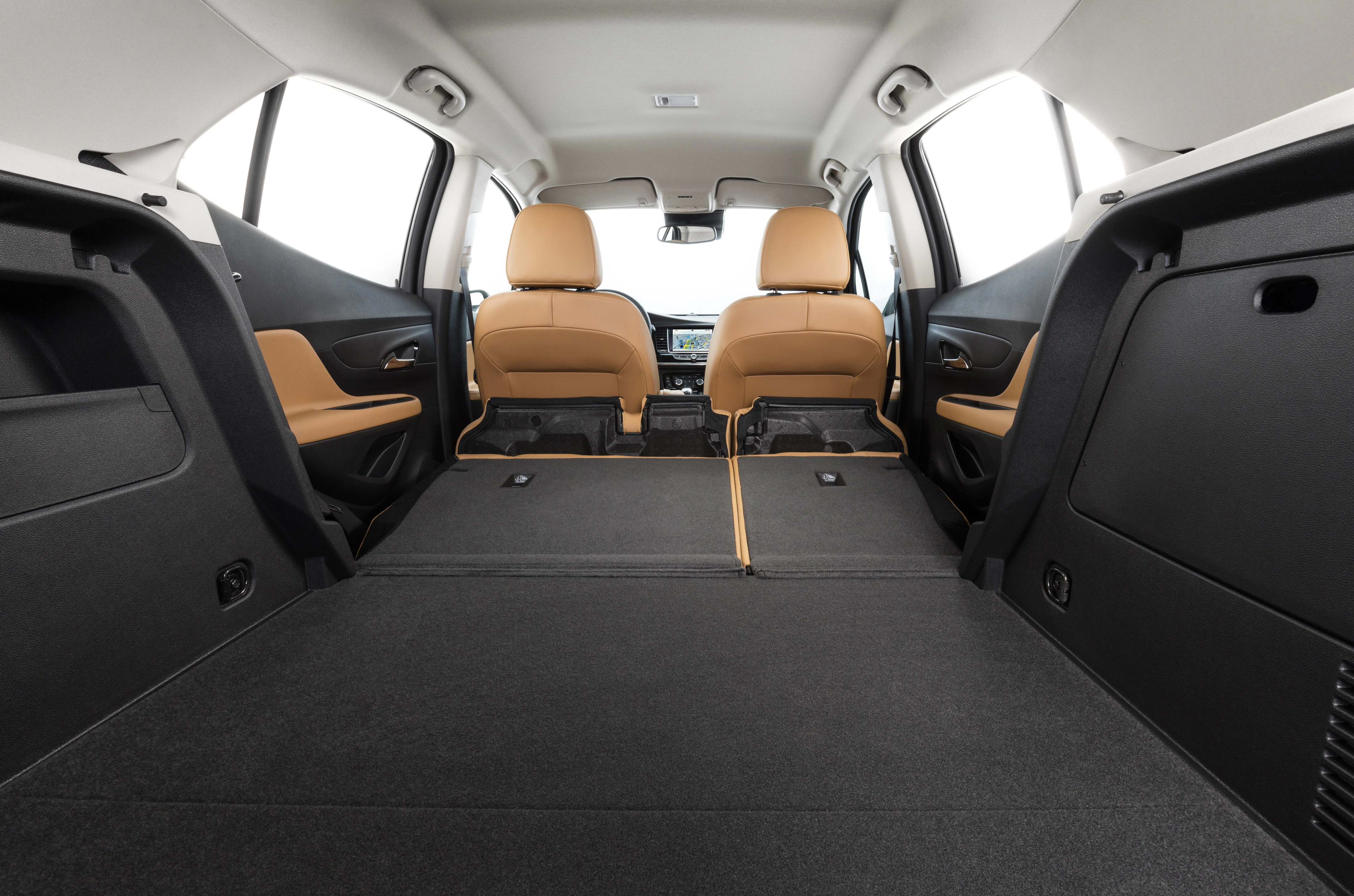 Rückansicht eines Fahrzeuginnenraums mit umgeklappten Rücksitzen, die einen flachen Laderaum bilden. Beige Sitze und moderne Ausstattung sichtbar.