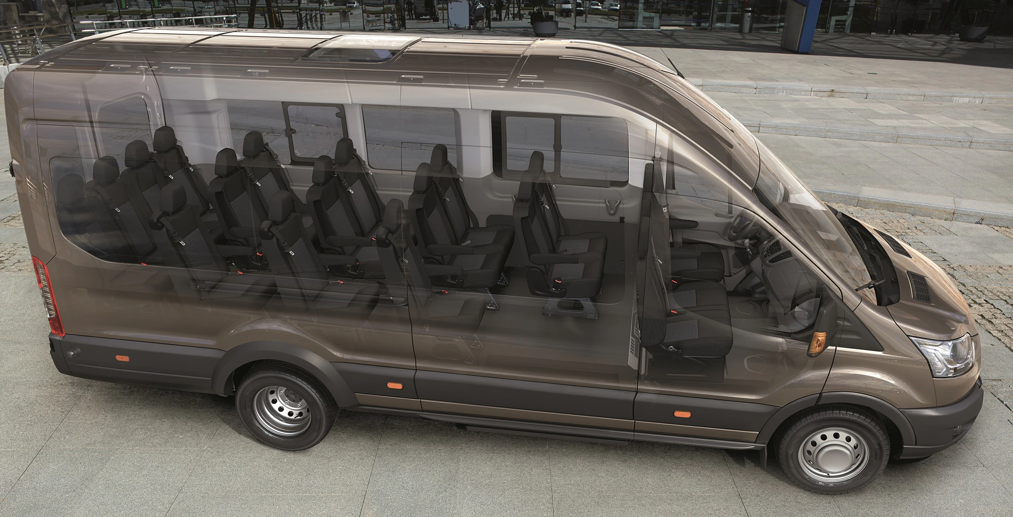 Ein brauner Minibus mit transparentem Effekt, der die Innenraum-Sitzanordnung zeigt. Parkt auf einer gepflasterten Fläche.
