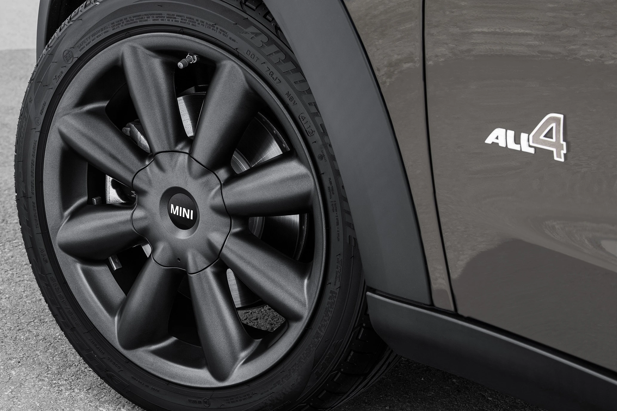 Nahaufnahme eines schwarzen Autoreifens mit Markenlogo und der Aufschrift "ALL4" auf der Karosserie.