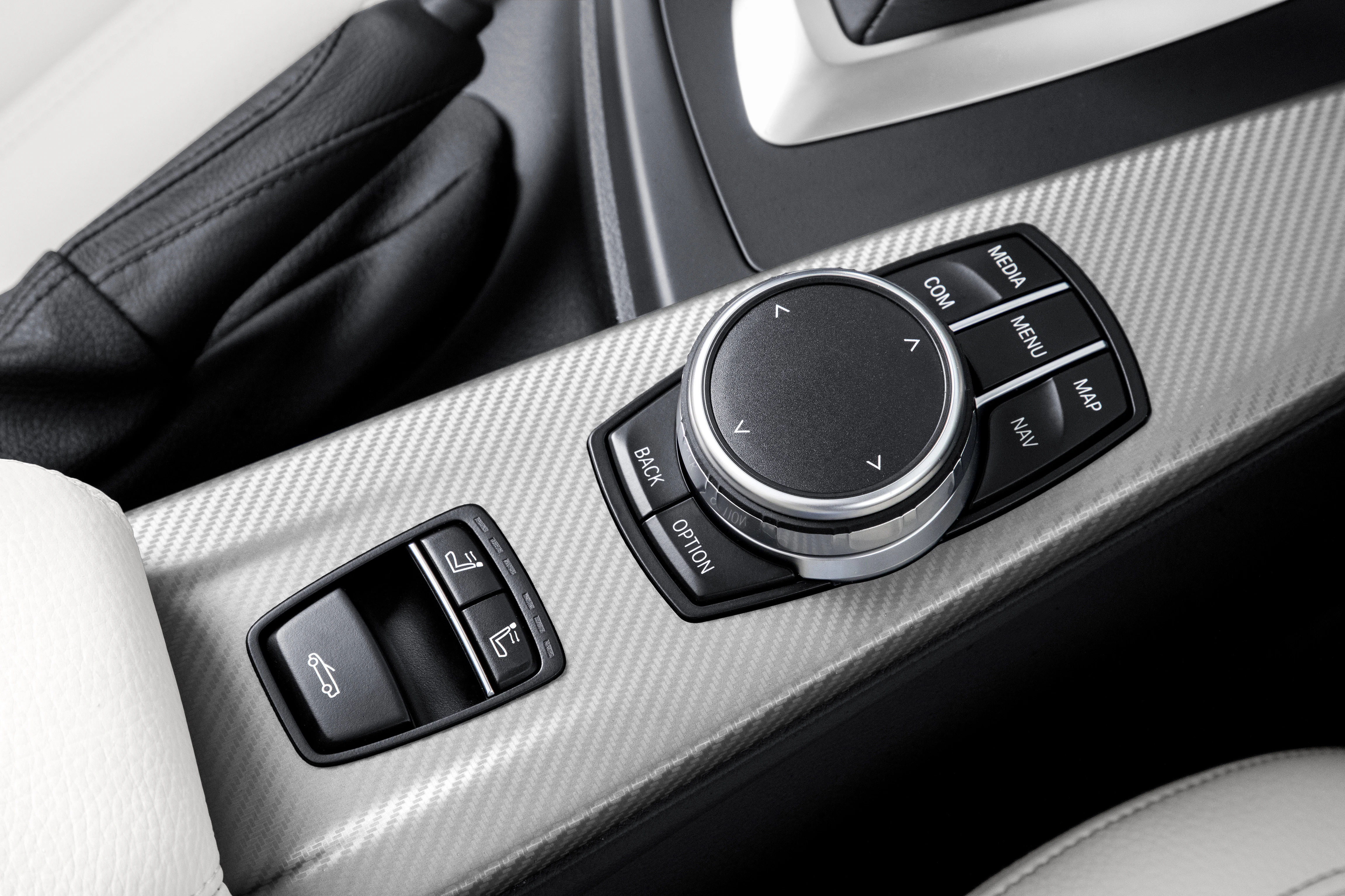 Nahaufnahme einer Autoschaltkonsole mit Drehknopf zur Navigation und Knöpfen für Rückwärts, Option und ein Autoöffner-Symbol.