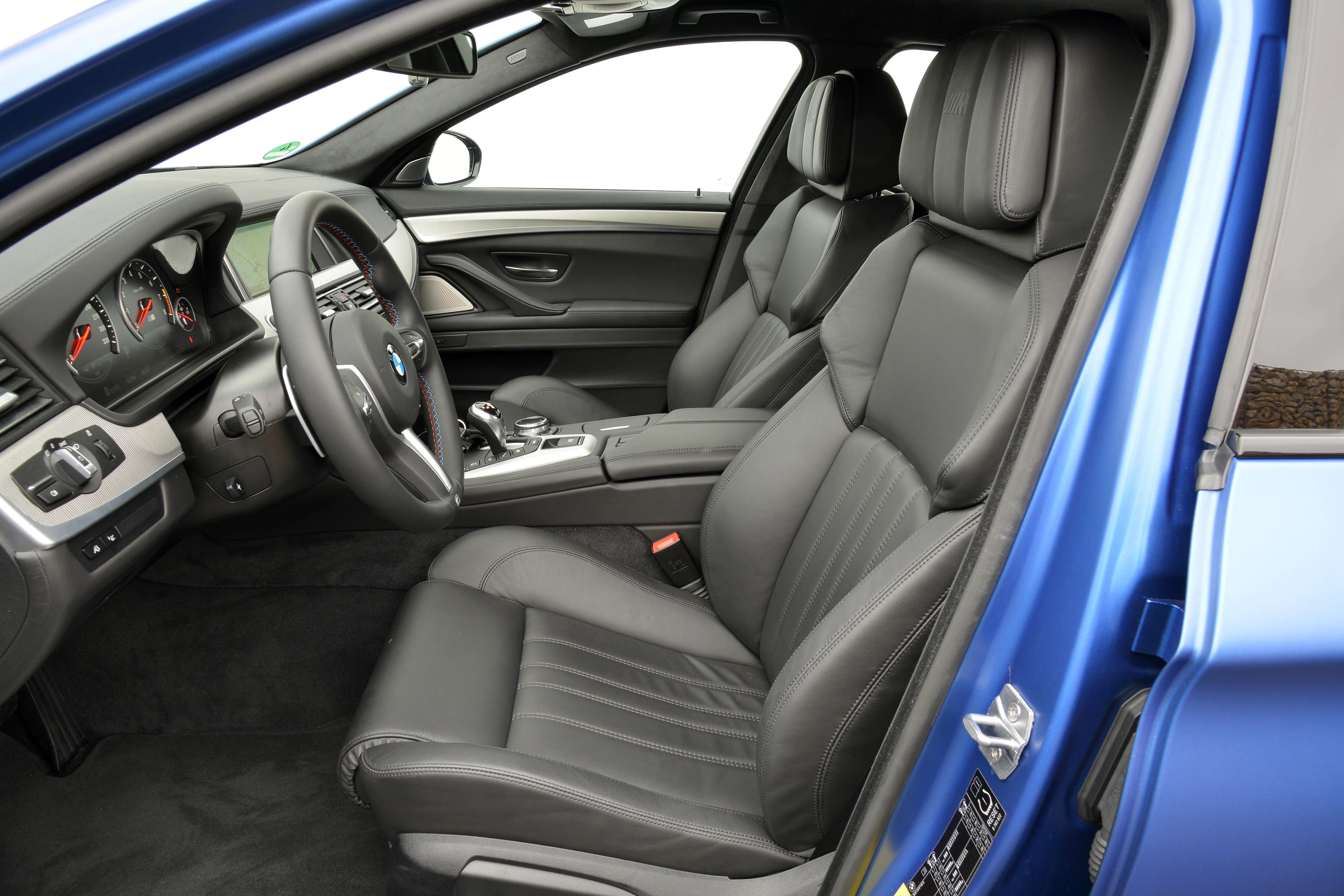 Blauer PKW mit modernem, schwarzem Ledersitz-Interieur, sichtbares Armaturenbrett mit Tachometer, Lenkrad und Mittelkonsole.
