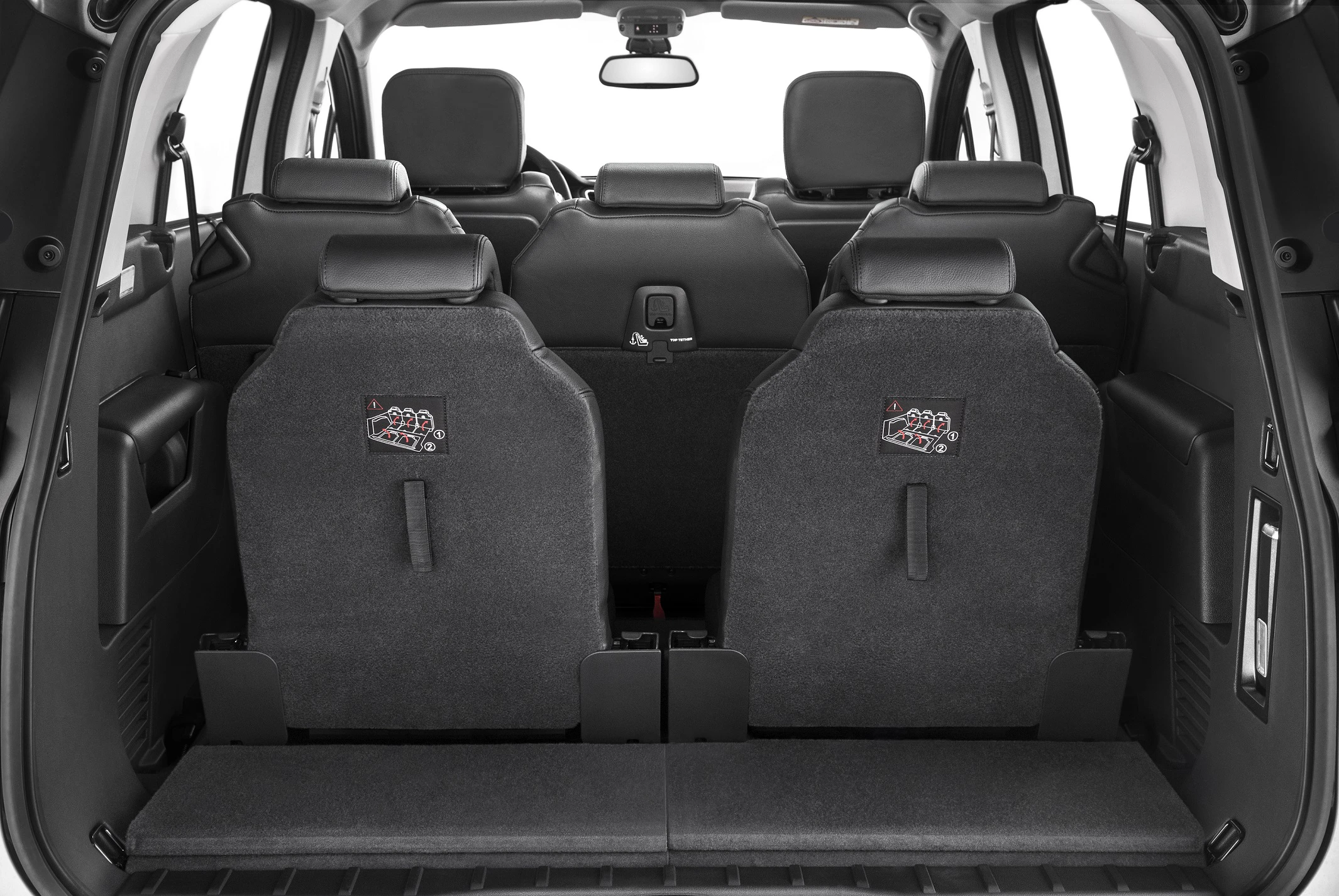 Blick auf den Innenraum eines Autos von hinten, mit umklappbaren Rücksitzen, die hochgestellt sind, und sichtbarem Kofferraum.