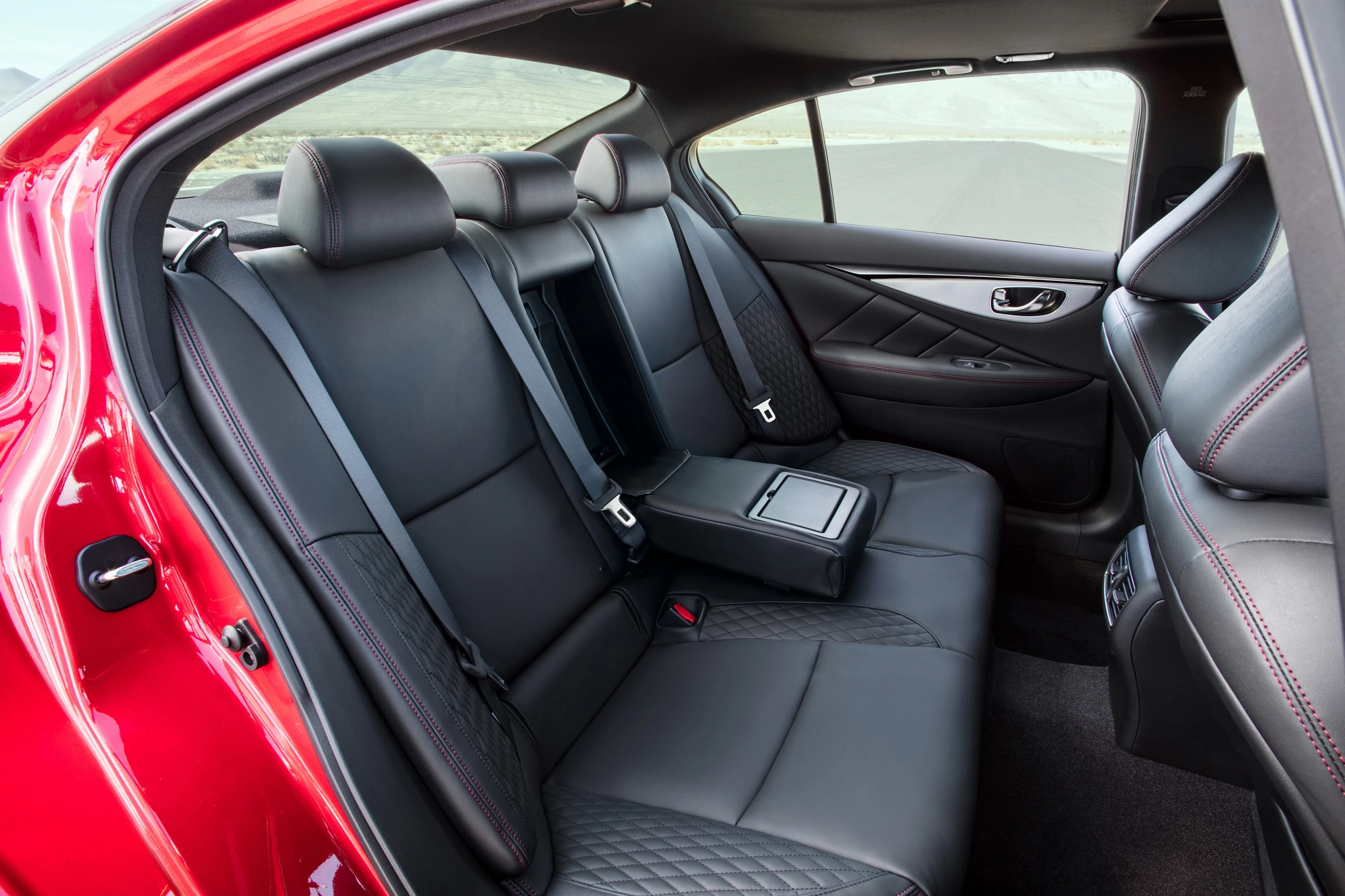 Rückansicht eines Autos mit drei schwarzen Ledersitzen, zwei Kopfstützen und Sicherheitsgurten; rote Autotür und Detailnähte sichtbar.