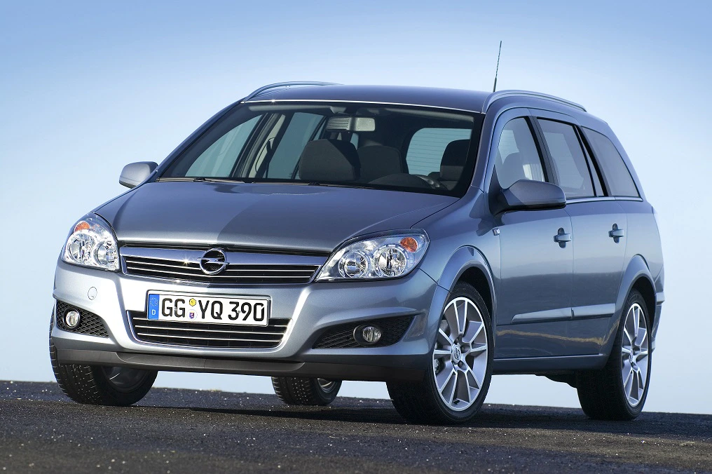 Silberner Opel Kombi auf offenem Asphalt, seitliche Frontansicht bei klarem Himmel. Automodell mit charakteristischen Scheinwerfern und Felgen.
