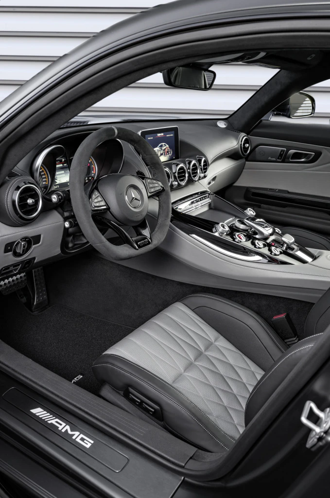 Innenraum eines eleganten Mercedes-AMG mit schwarzem Lenkrad, grau-schwarzen Sitzen und moderner Instrumententafel.