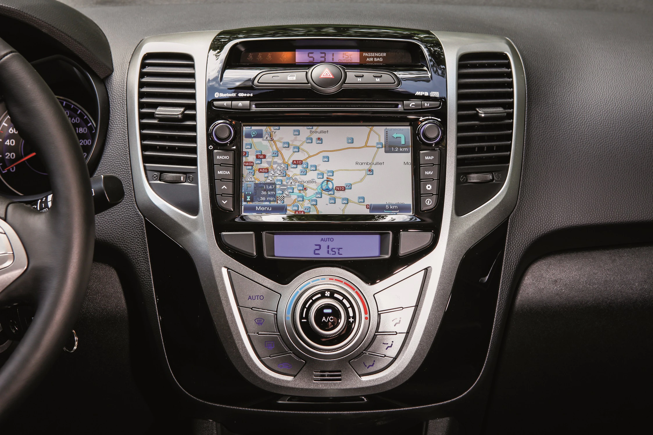 Navigationssystem in einem Auto, zeigt eine digitale Karte auf dem Display. Darunter Bedienelemente für Radio und Klimaanlage.
