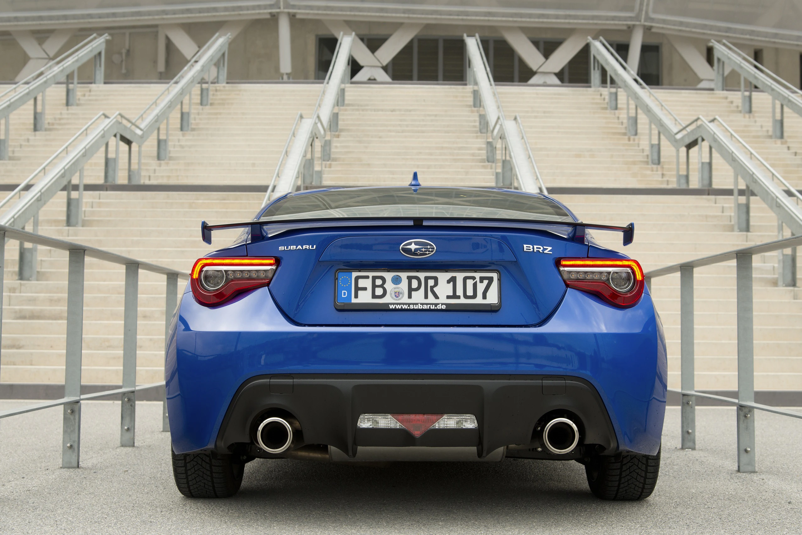 Blauer Subaru BRZ von hinten vor Treppe, mit auffälligem Spoiler und Auspuff. Fahrzeugkennzeichen sichtbar.