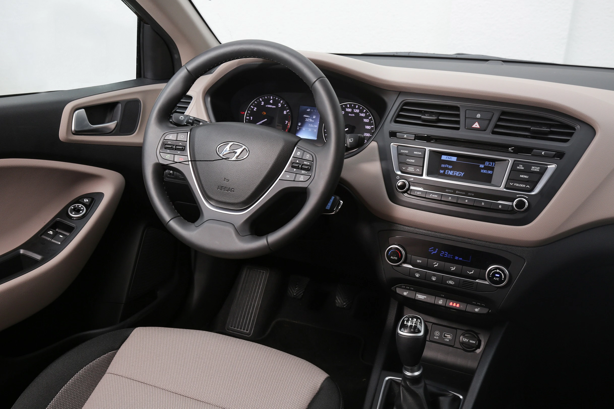 Innenraum eines Autos mit Lenkrad, Tachometer und Mittelkonsole. Elegantes Design mit Tasten für Radio, Klimaanlage und Schaltknauf.
