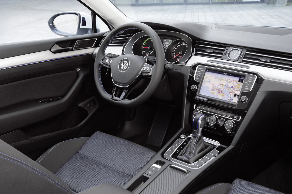 Innenansicht eines modernen Autos mit Navigationssystem, Lenkrad und Schalthebel. Europäische Instrumententafel und Lederdetails sichtbar.