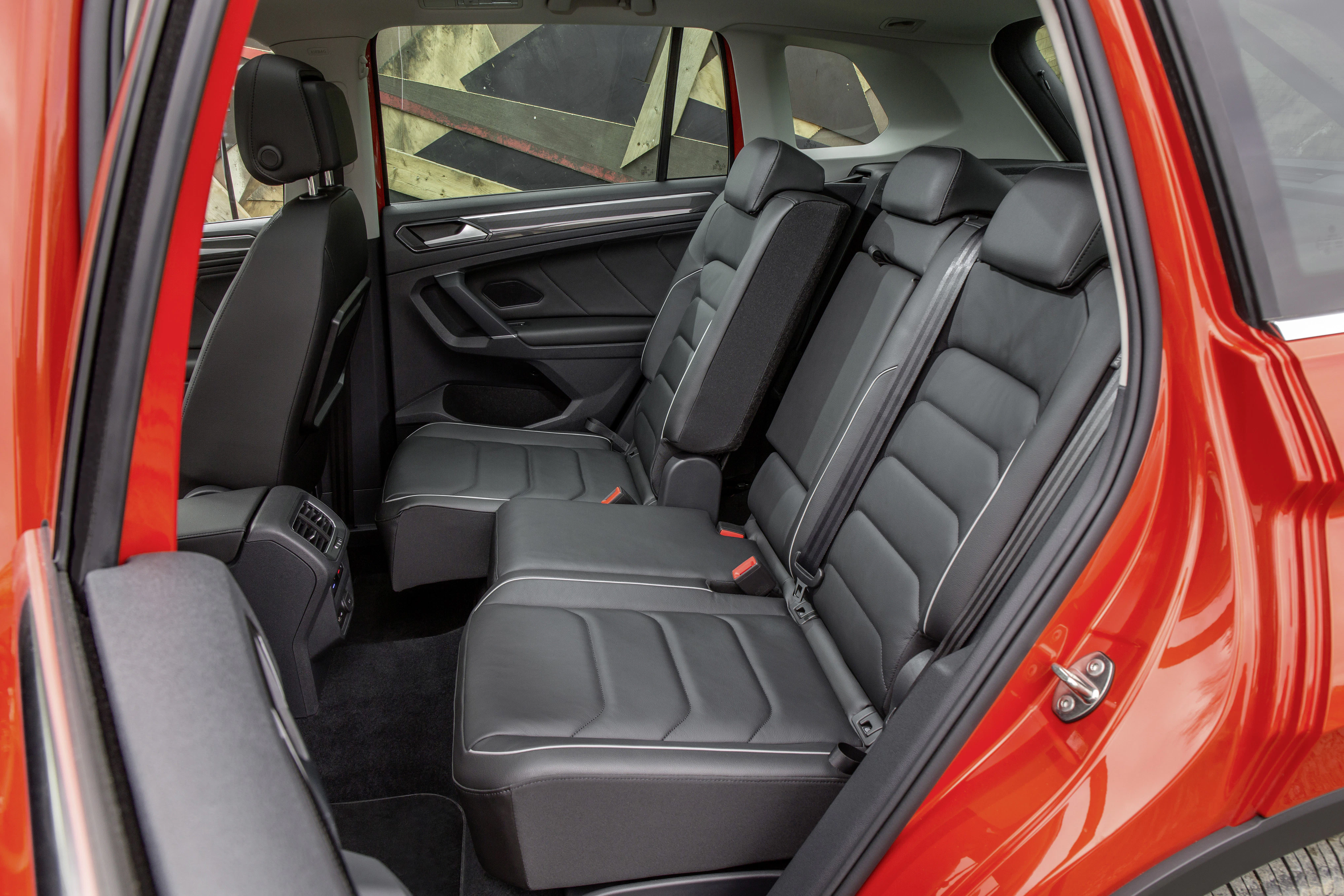 Rückansicht eines Autos mit roten Türen. Sicht auf schwarze Ledersitze und Innenraumdetails. Sitze in zwei Reihen für Passagiere.