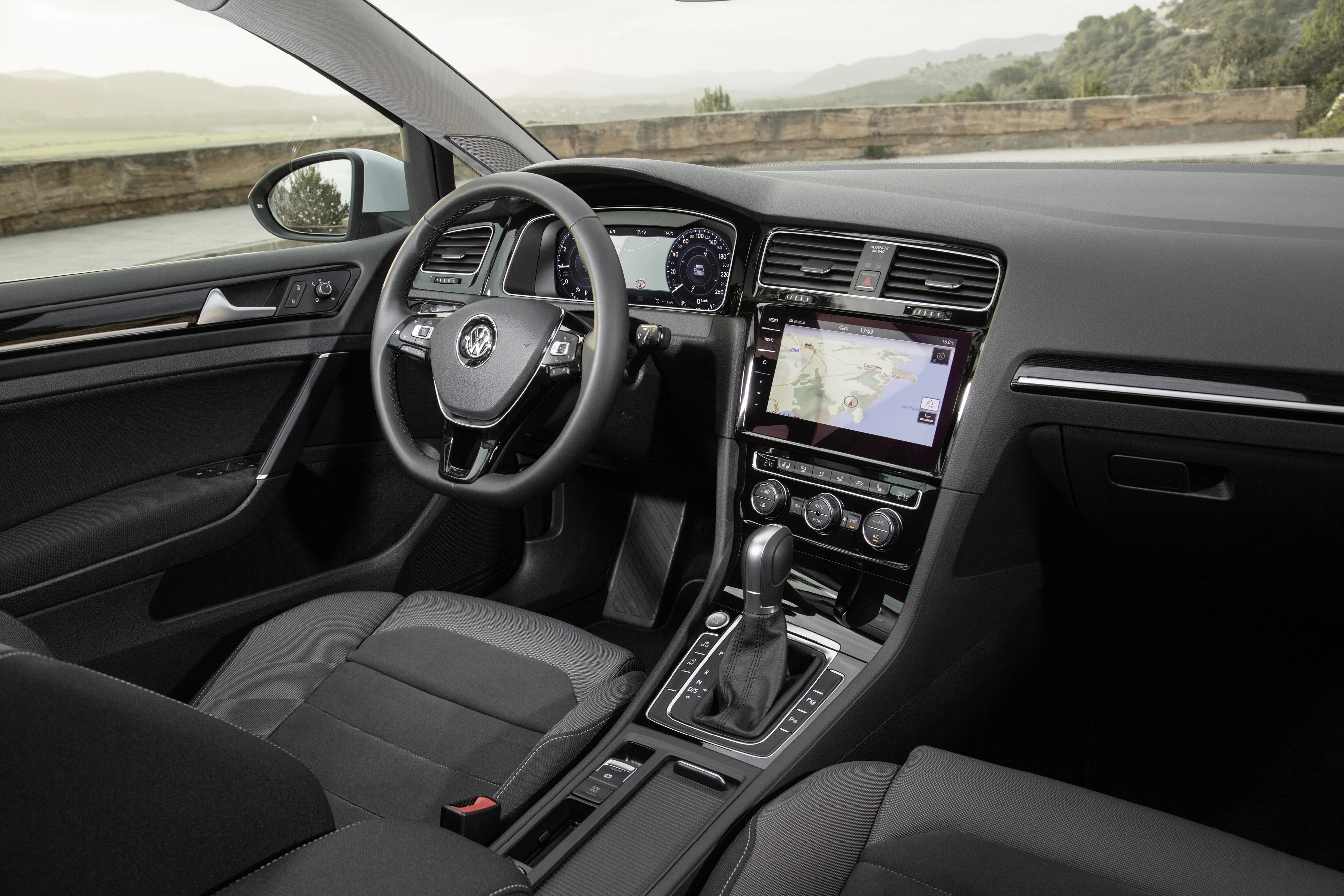 Innenraum eines modernen Autos mit einem digitalen Armaturenbrett, Navigation auf dem Bildschirm und einem Lenkrad mit Markenlogo.