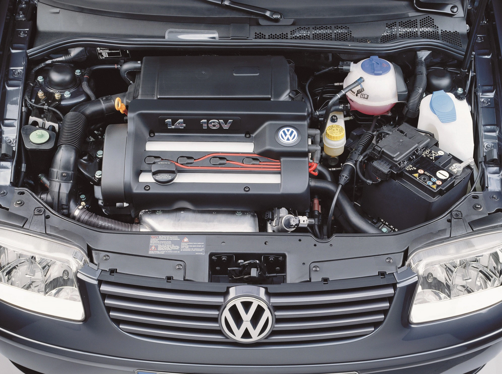 Motorraum eines Volkswagen mit sichtbarem 1.4 16V-Motor, Batterie und verschiedenen Flüssigkeitsbehältern.