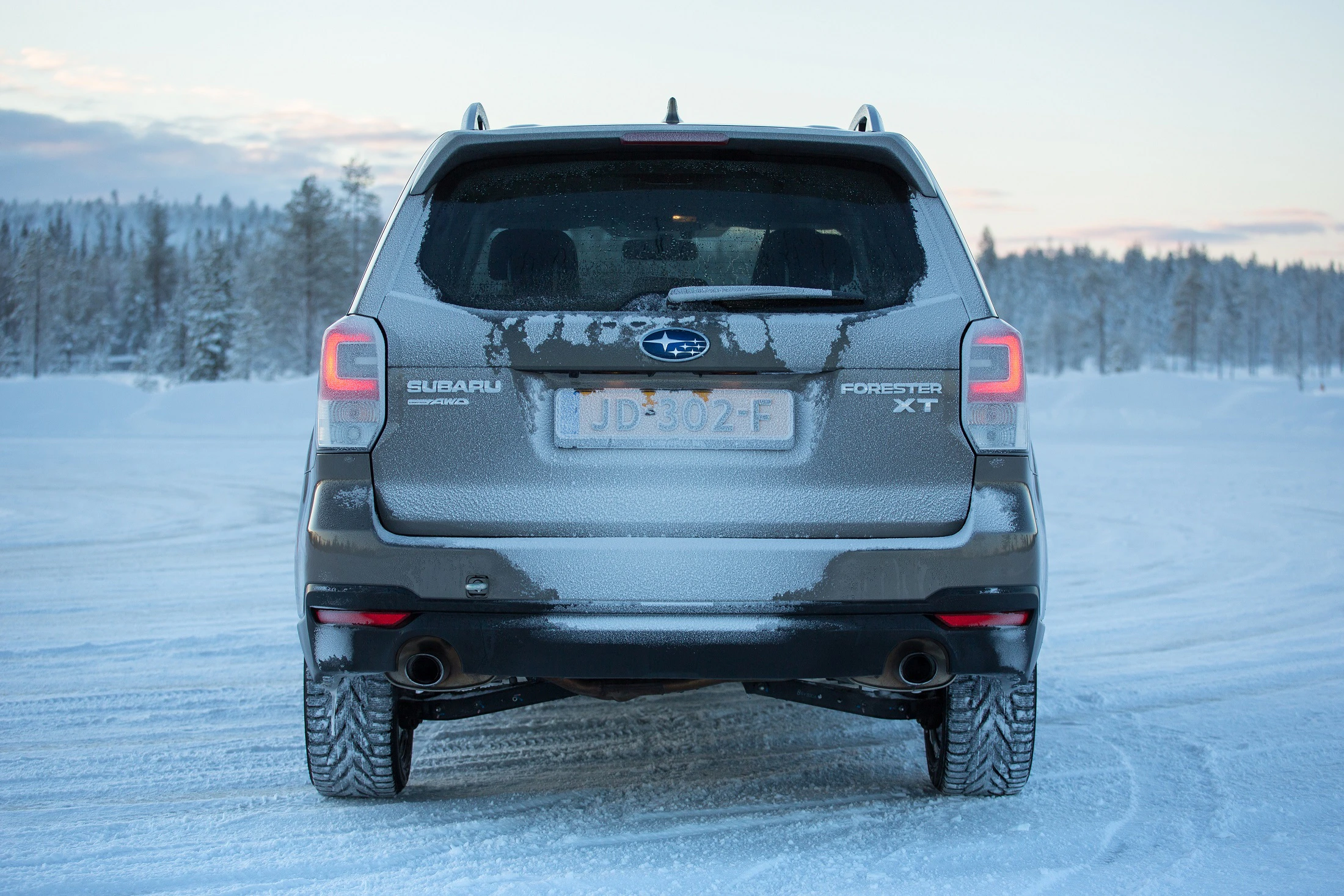 Rückansicht eines Subaru Forester XT im Schnee, bedeckt mit Frost. Winterlandschaft im Hintergrund, klare Himmel.