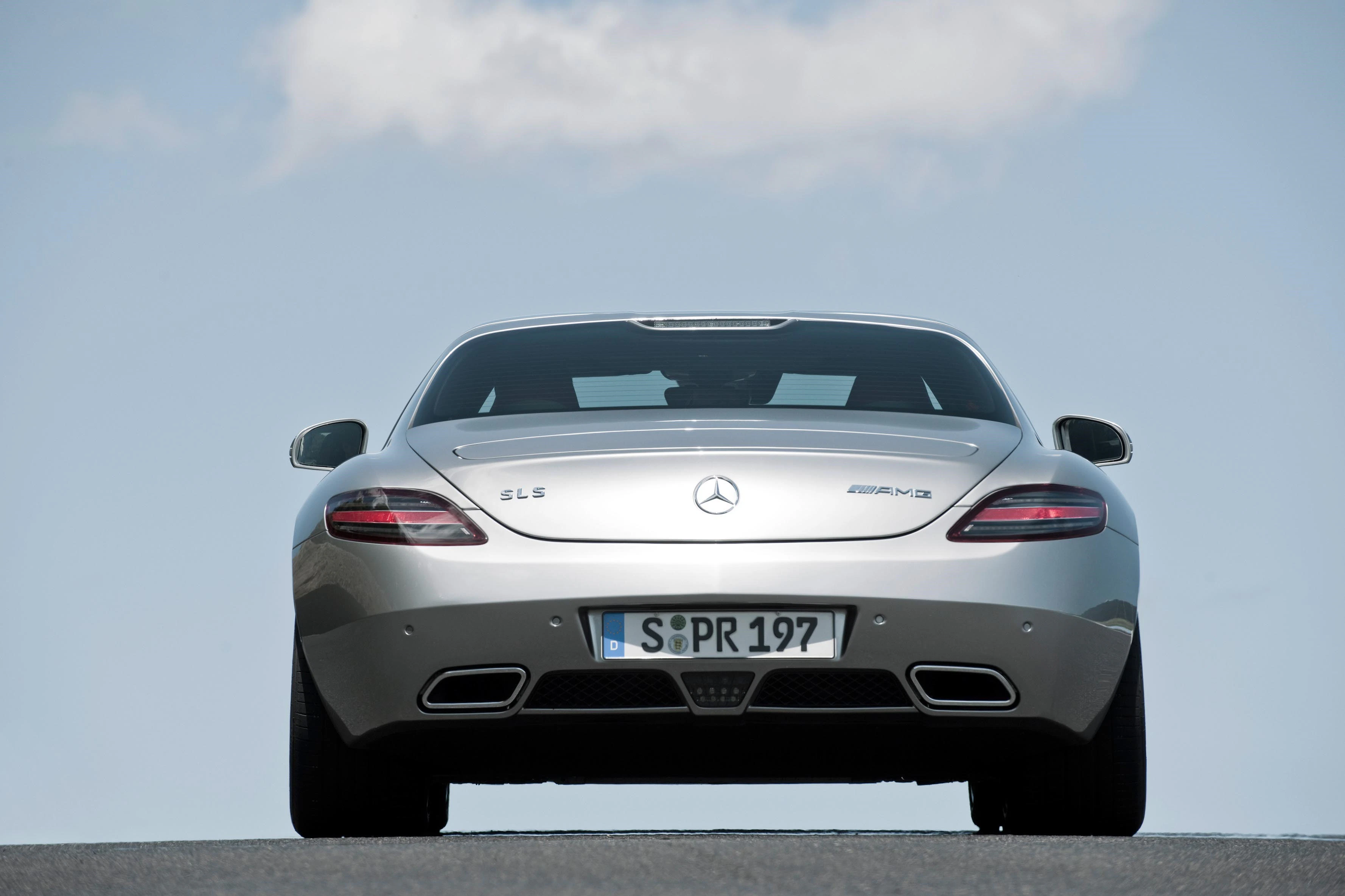 Silberner Mercedes-Benz SLS AMG von hinten, aufgenommen aus einer niedrigen Perspektive vor klarem Himmel.